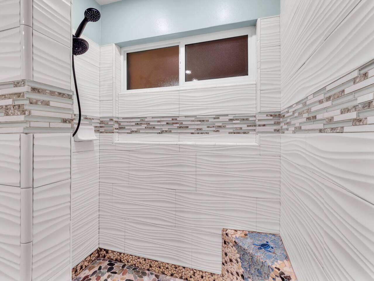 The stunning custom shower in the master bath features unique stone and shell elements, blending nature with luxury.