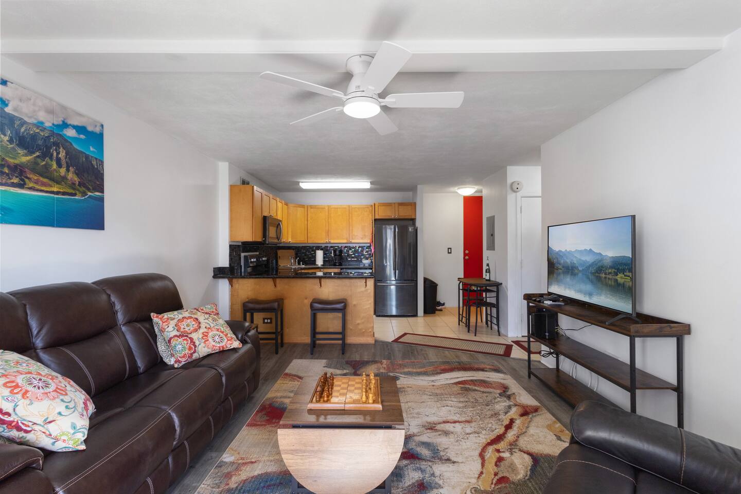 The spacious open-layout living area is perfect for personal relaxation or hosting guests, with comfortable seating, a large TV, and seamless flow into the fully equipped kitchen.