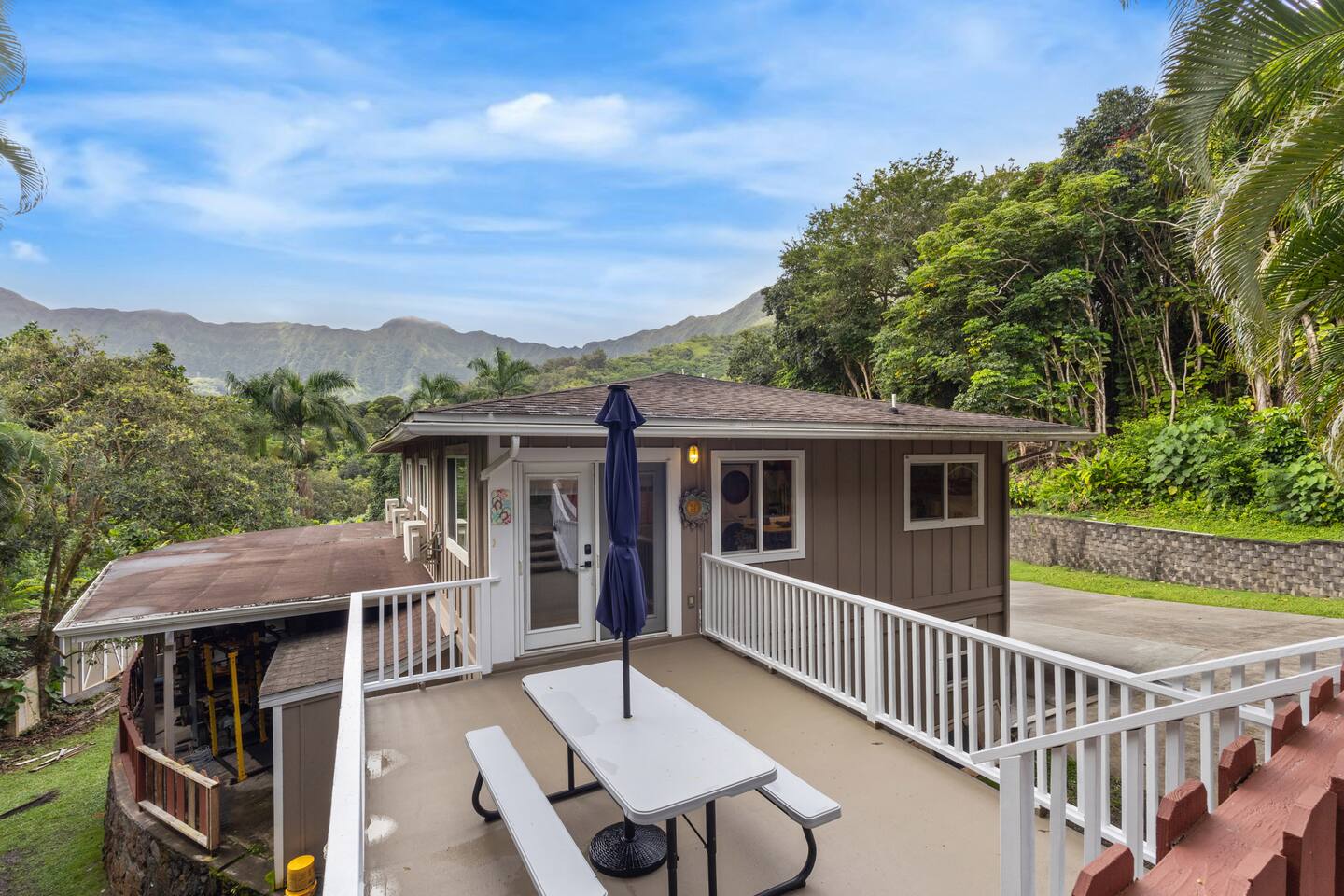 A charming vacation home nestled in lush greenery, featuring a spacious outdoor deck.
