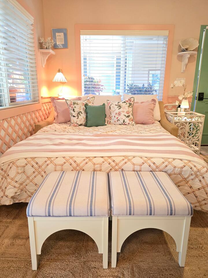 Where comfort meets charm: floral pillows, striped benches, and a bed that feels like a warm hug