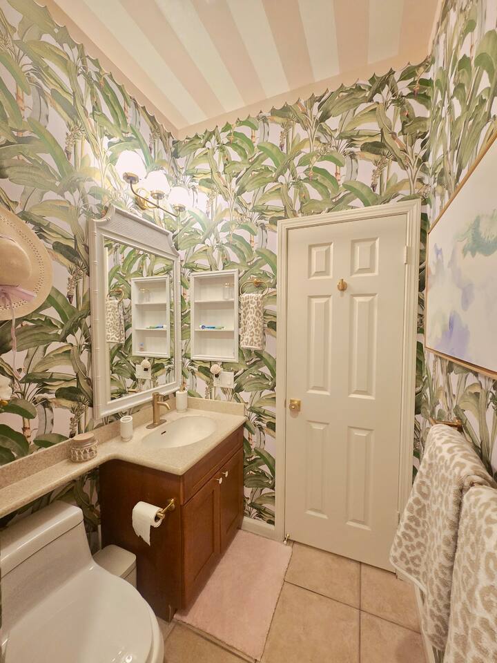 Bold botanicals and pastel charm this tropical-inspired bathroom is a getaway all its own