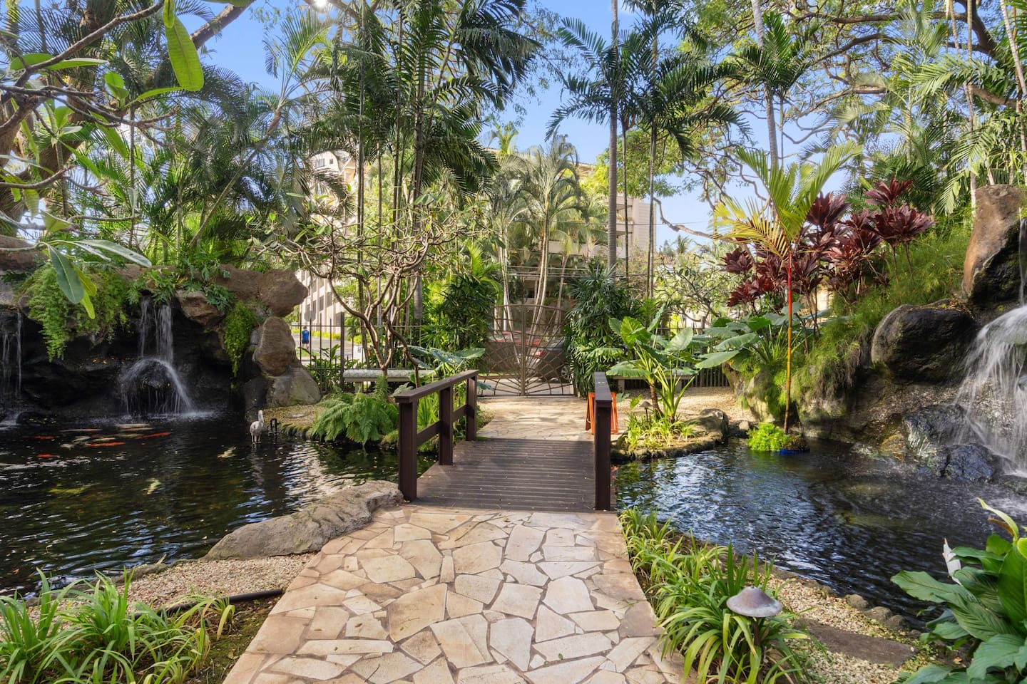 Stone paths, lush greens, and water’s whisper. This courtyard blends nature with grace. Your peaceful pause, just steps away.