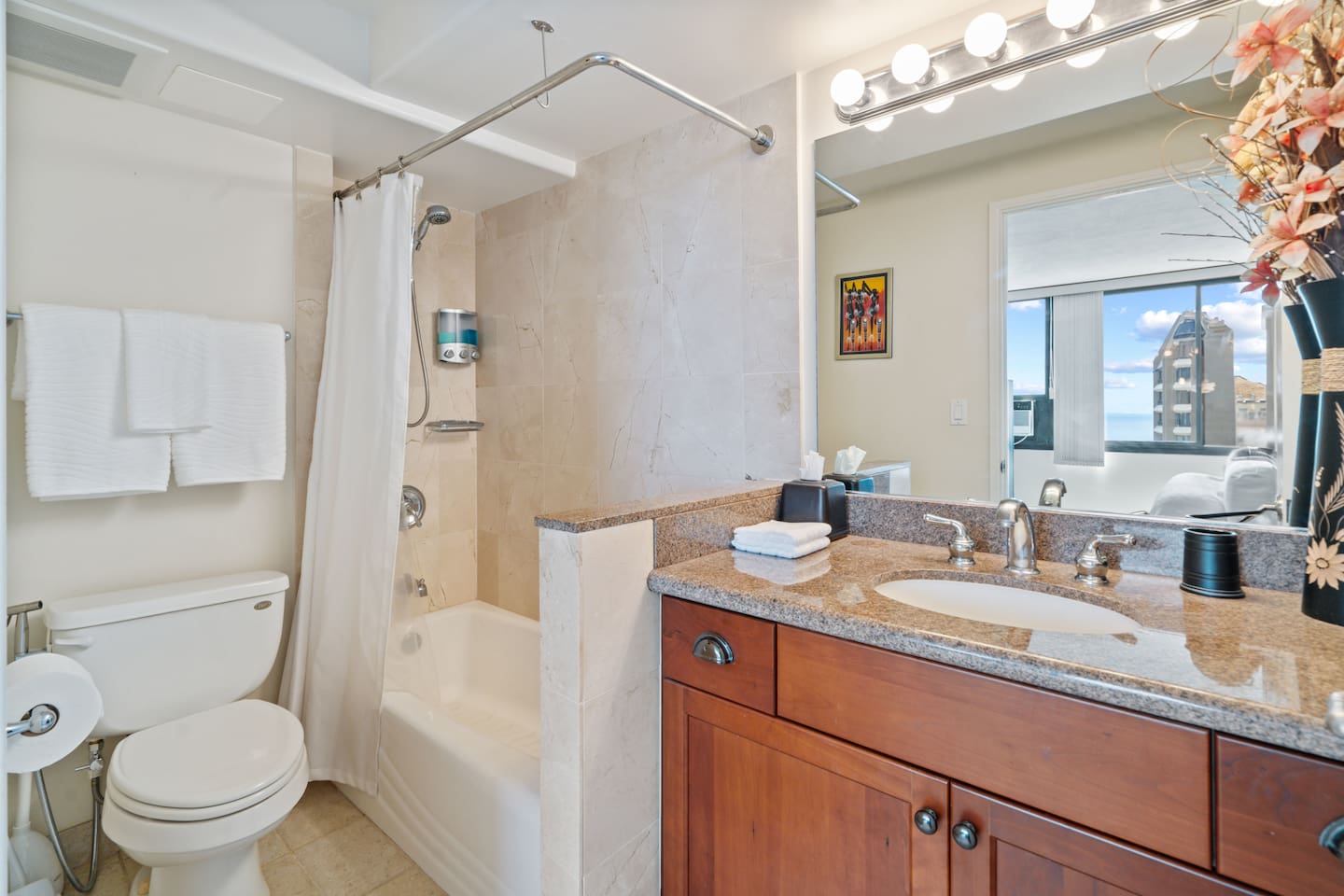 Bright mornings start right here. Towels fluffed, flowers in bloom, and city sparkle beyond. This bathroom’s got charm.