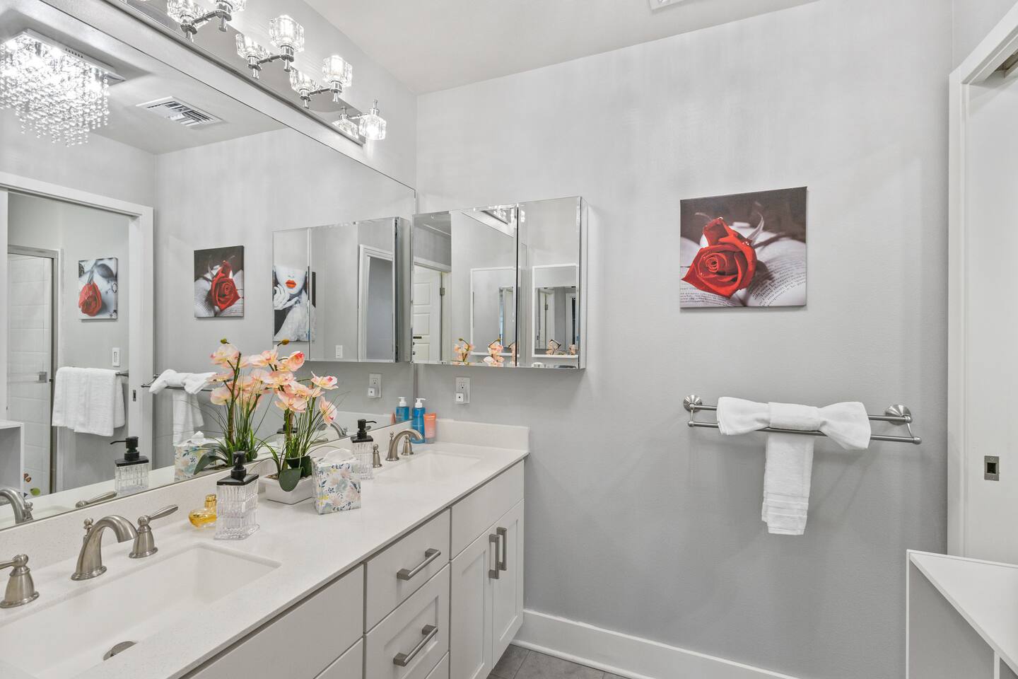 Crystal lighting, floral accents, and a double-sink layout make this bathroom feel polished and luxurious.