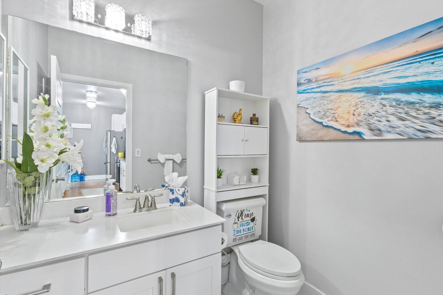 Decorative touches, soft florals, and a splash of ocean color make this bathroom feel like a retreat.