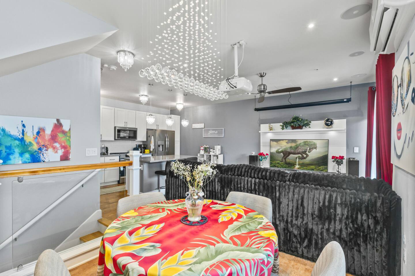 Open layout with dining, kitchen, and lounge areas accented by modern lighting and colorful decor.