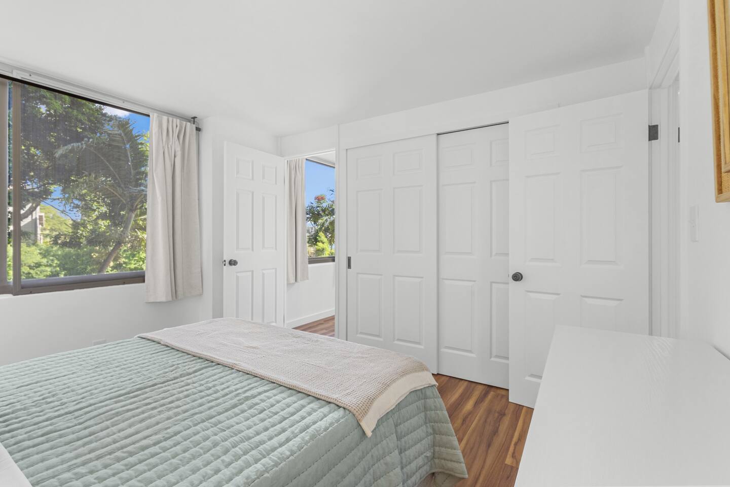A peaceful perch with a view, where soft green bedding and sunny windows set the tone for rest.