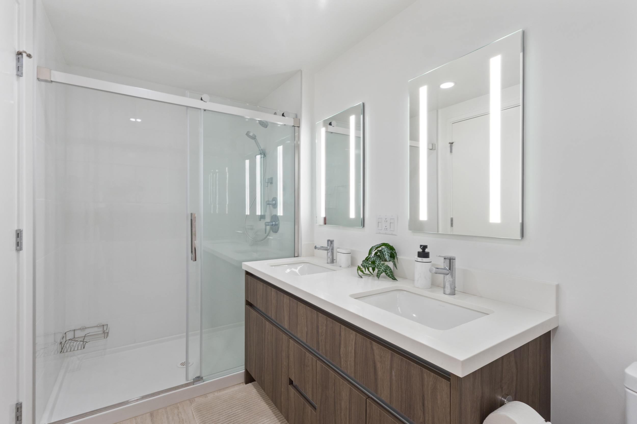 Bright modern bathroom with double vanity and glass walk-in shower