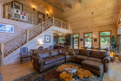 The rustic Great Room is the ultimate gathering space — dramatic vaulted ceilings, an open loft above, and a plush leather sectional create a warm and inviting atmosphere that pulls the whole group together.