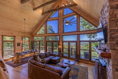 Floor-to-ceiling windows frame breathtaking mountain views while a grand stone fireplace anchors the room in warmth and character — creating a retreat that is as visually stunning as it is deeply relaxing.