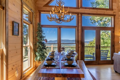 The rustic dining room is a meal-time experience like no other — vaulted windows frame breathtaking mountain views and direct deck access makes indoor and outdoor dining feel completely seamless at Rested Traveler.
