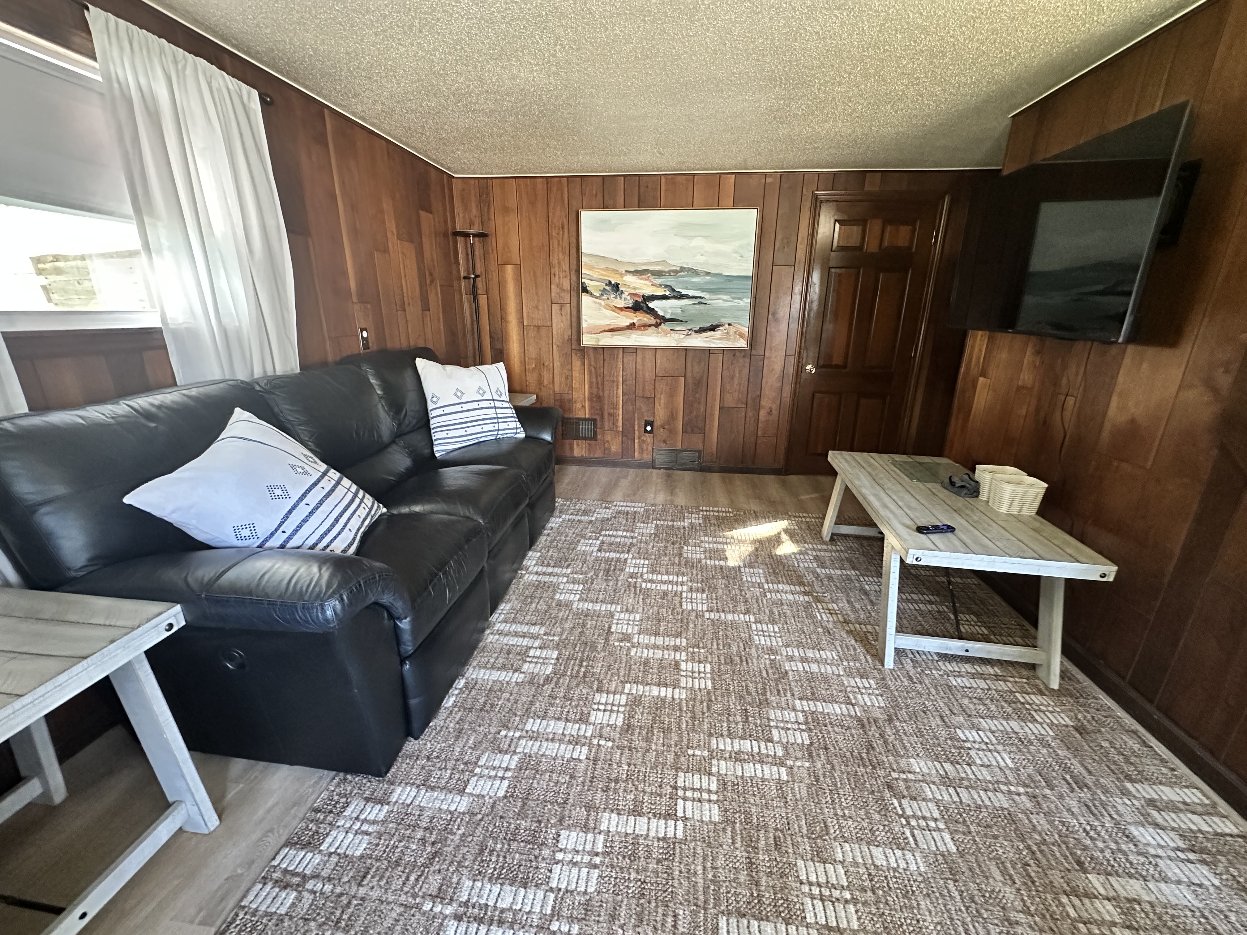 Cozy wood-paneled living room with big TV and comfy leather sofa