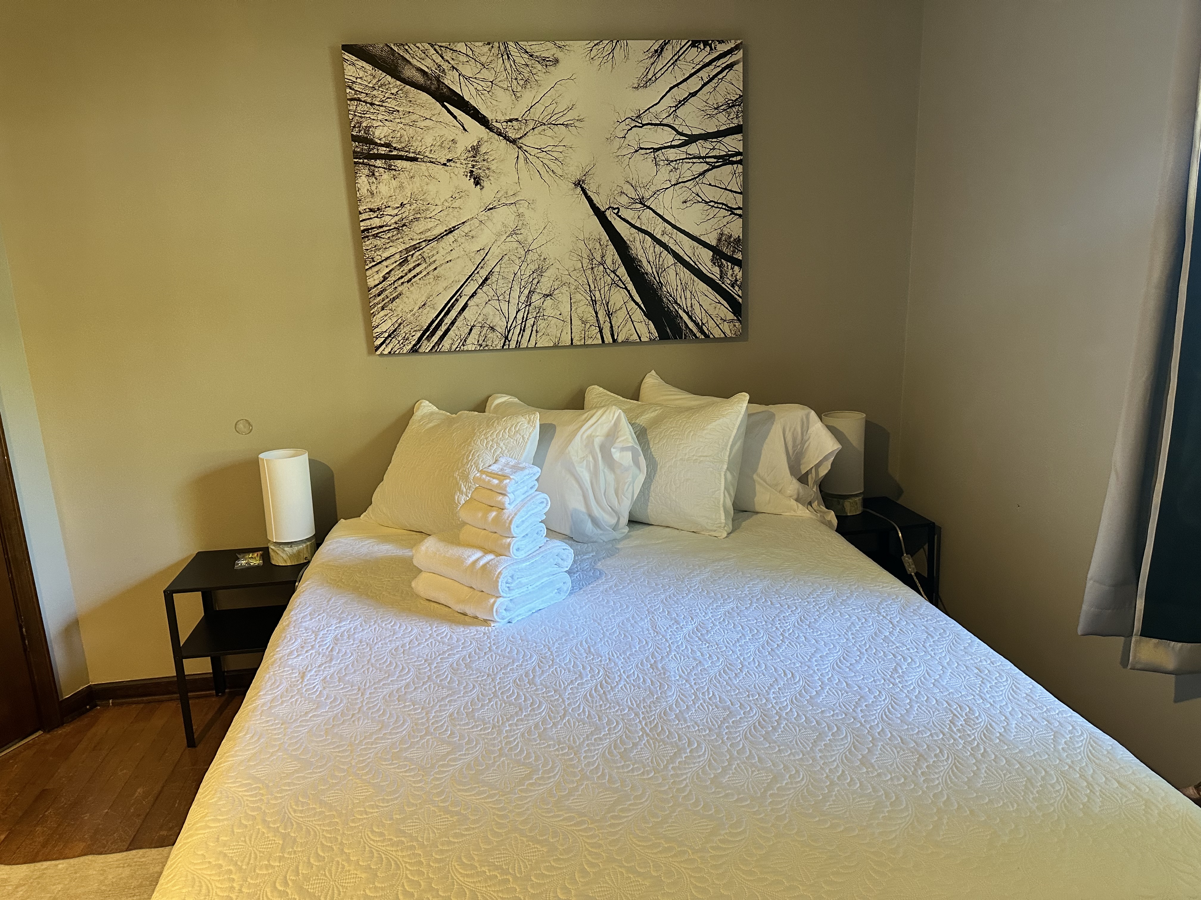 Cozy bedroom with fresh linens, bedside lamps, and serene wall art
