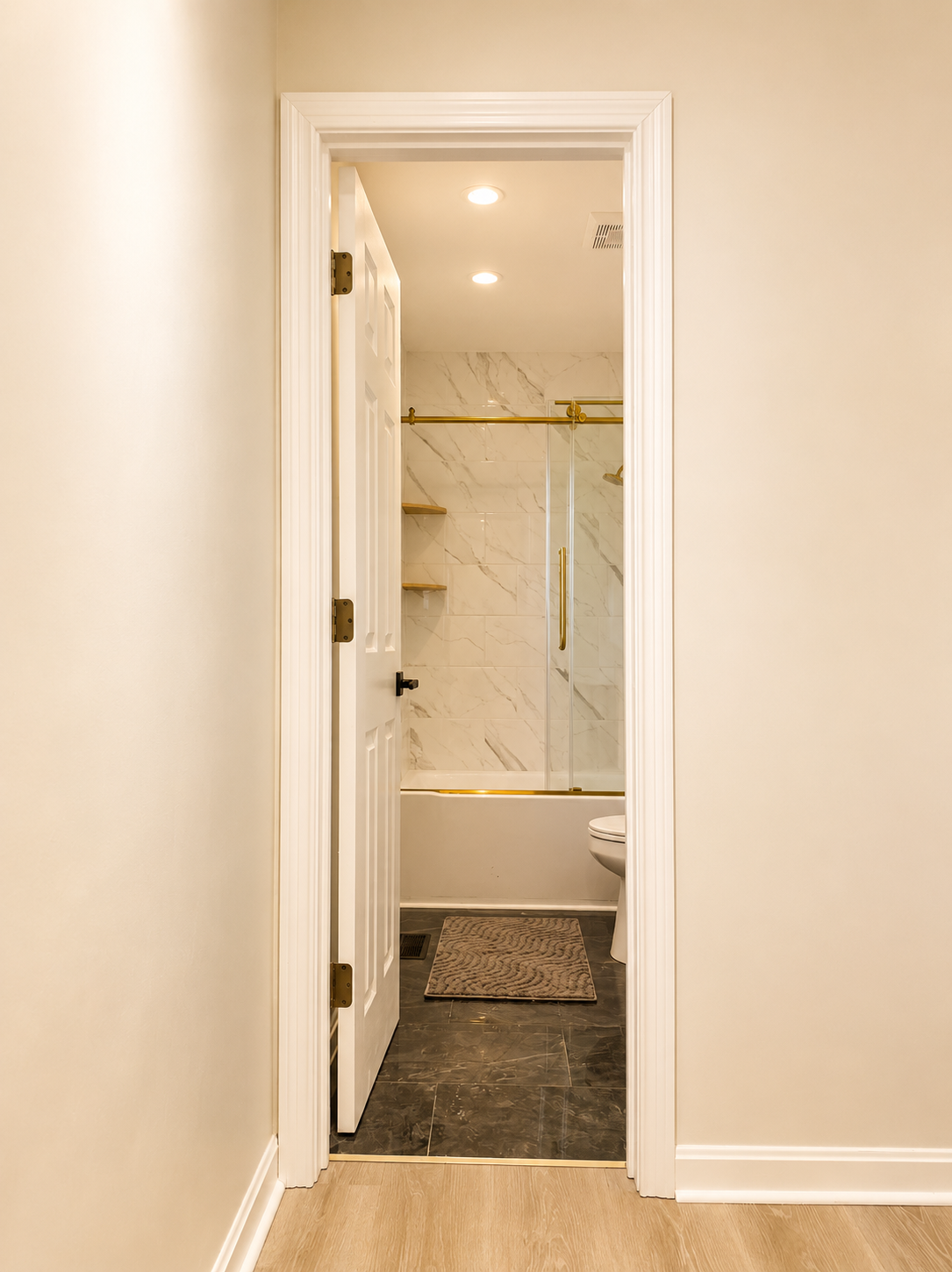 Modern marble-style bathroom with glass shower and elegant gold accents