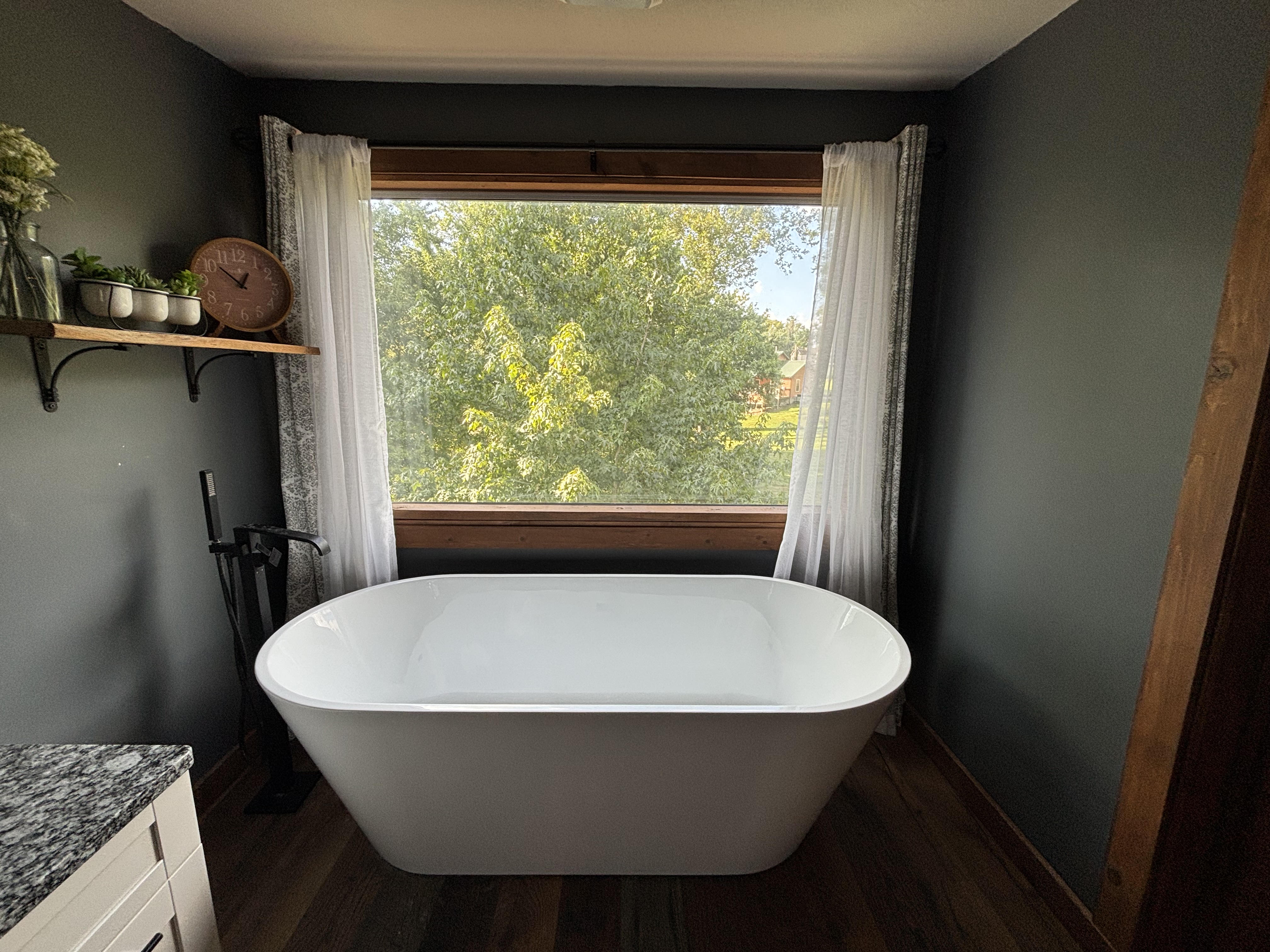 Spa-like soaking tub with large picture window and peaceful treetop views
