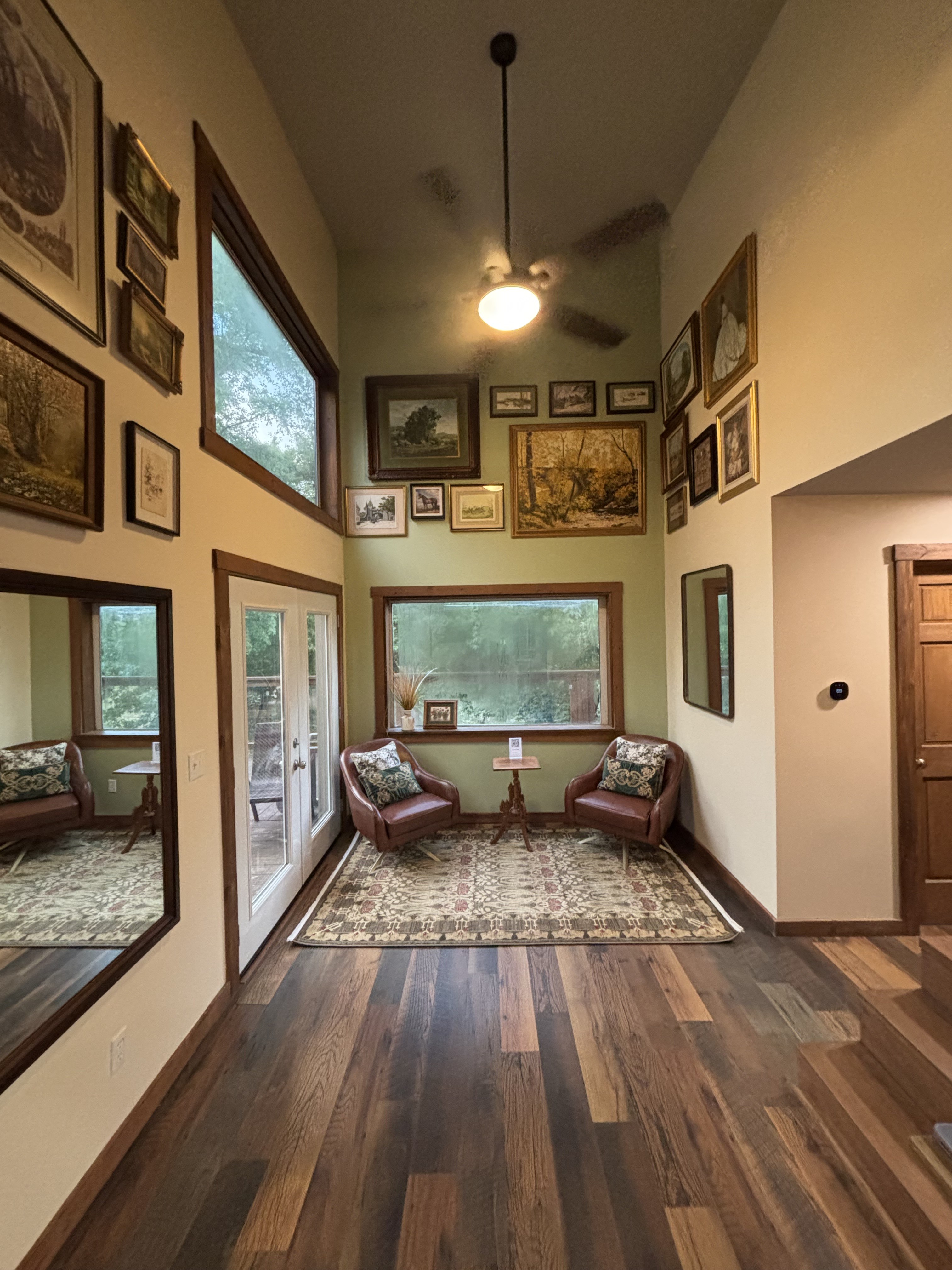 Warm, art-filled entry lounge with leather chairs and wooded views