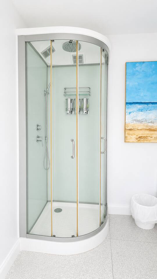 Clean walk-in glass shower stocked with shampoo, conditioner, and body wash for your convenience.