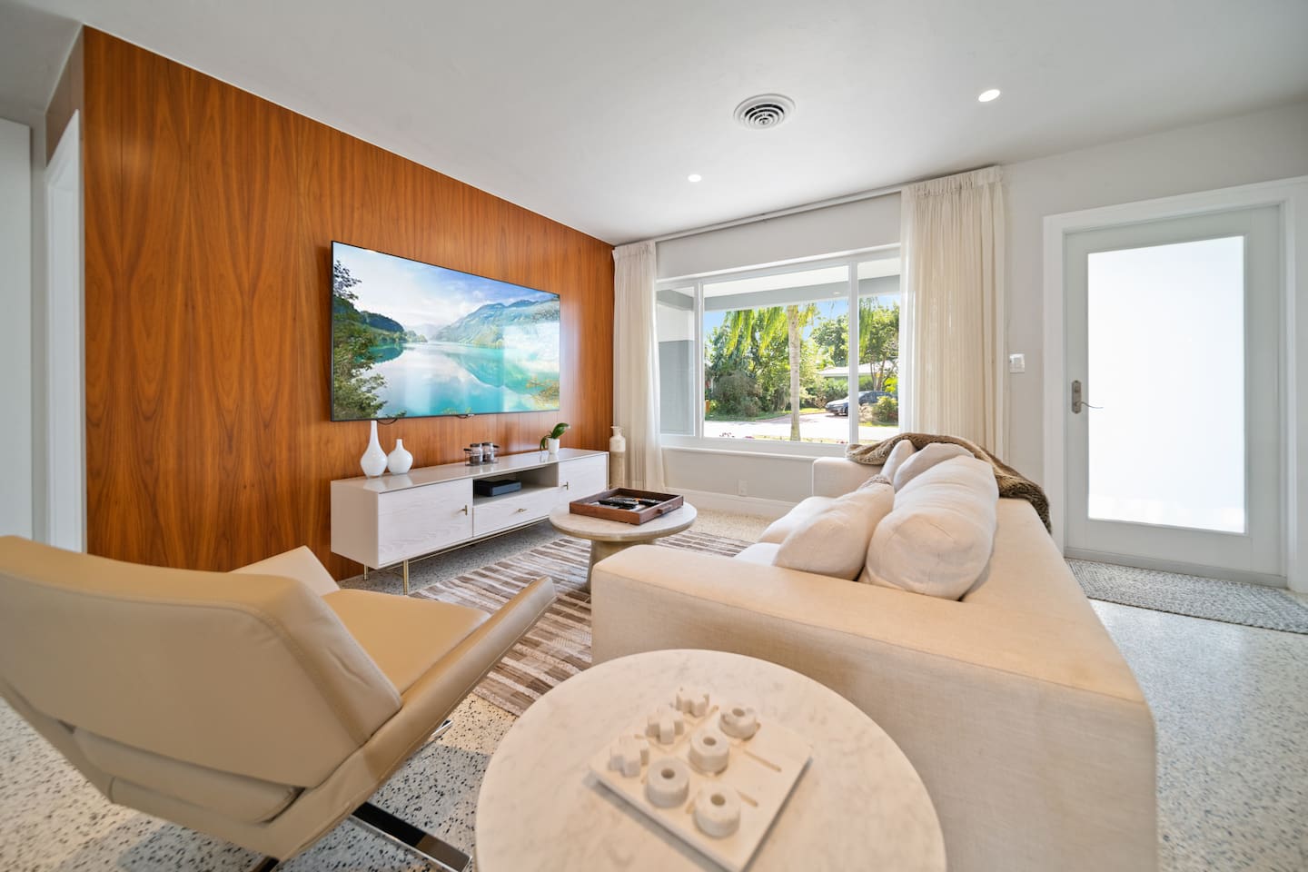 Relax in the bright and inviting living room featuring a plush sofa, stylish seating, and a 65-inch Smart TV. The open layout creates the perfect space to unwind after a day exploring Fort Lauderdale.
