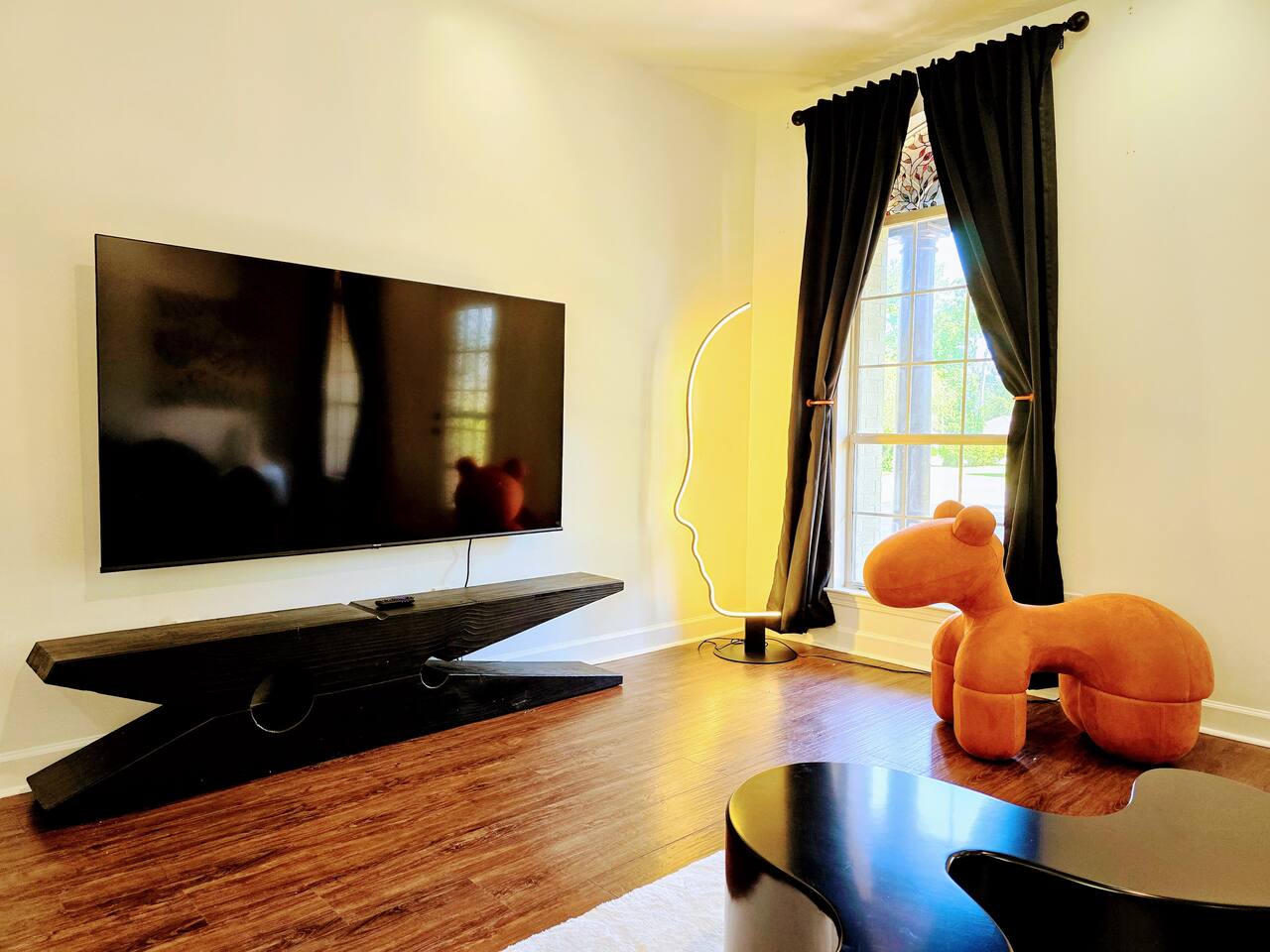 The large living room is well adorned with unique furniture sourced from around the globe. Every item has been carefully chosen for their quality, comfort, and design characteristics.