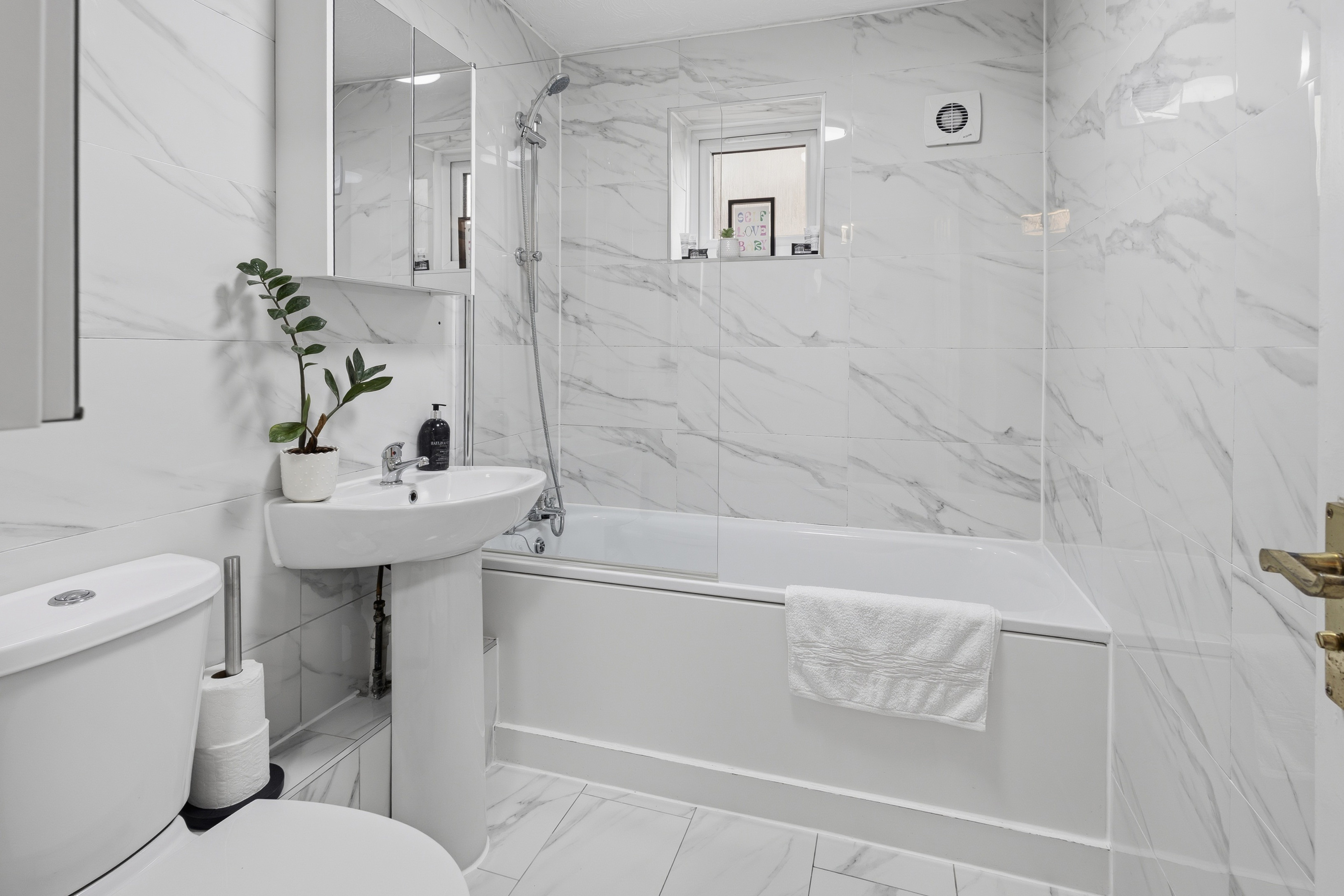 Sleek marble-style bathroom with tub, shower, and bright modern finish