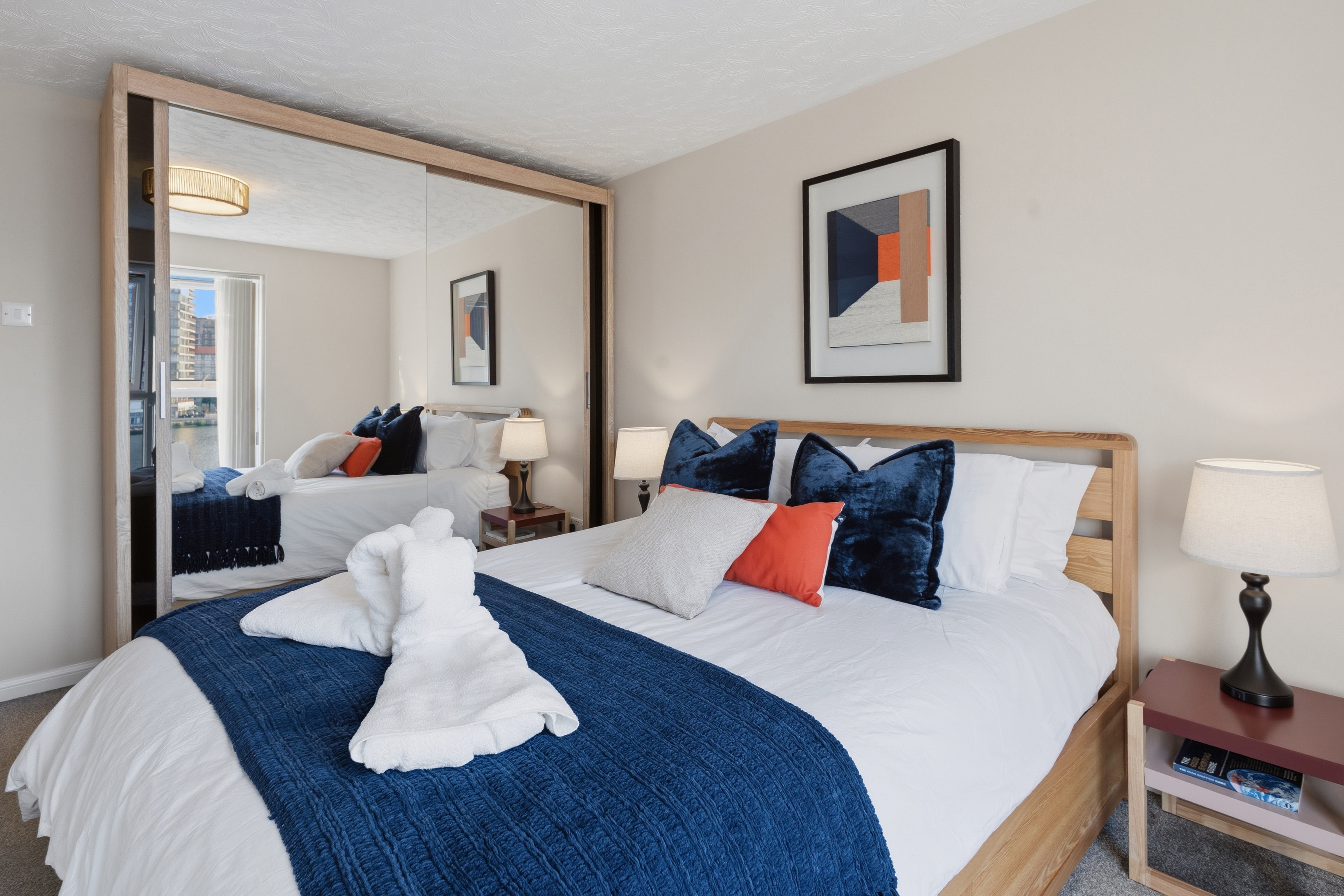 Bright modern bedroom with mirrored closets and stylish blue accents