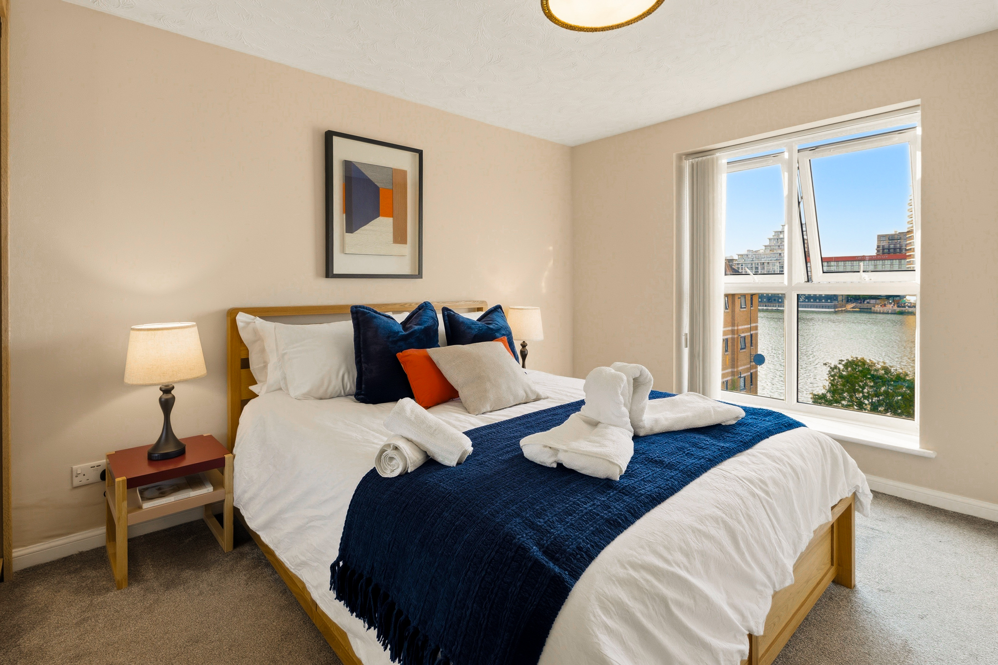 Bright waterfront bedroom with cozy styling and scenic city views