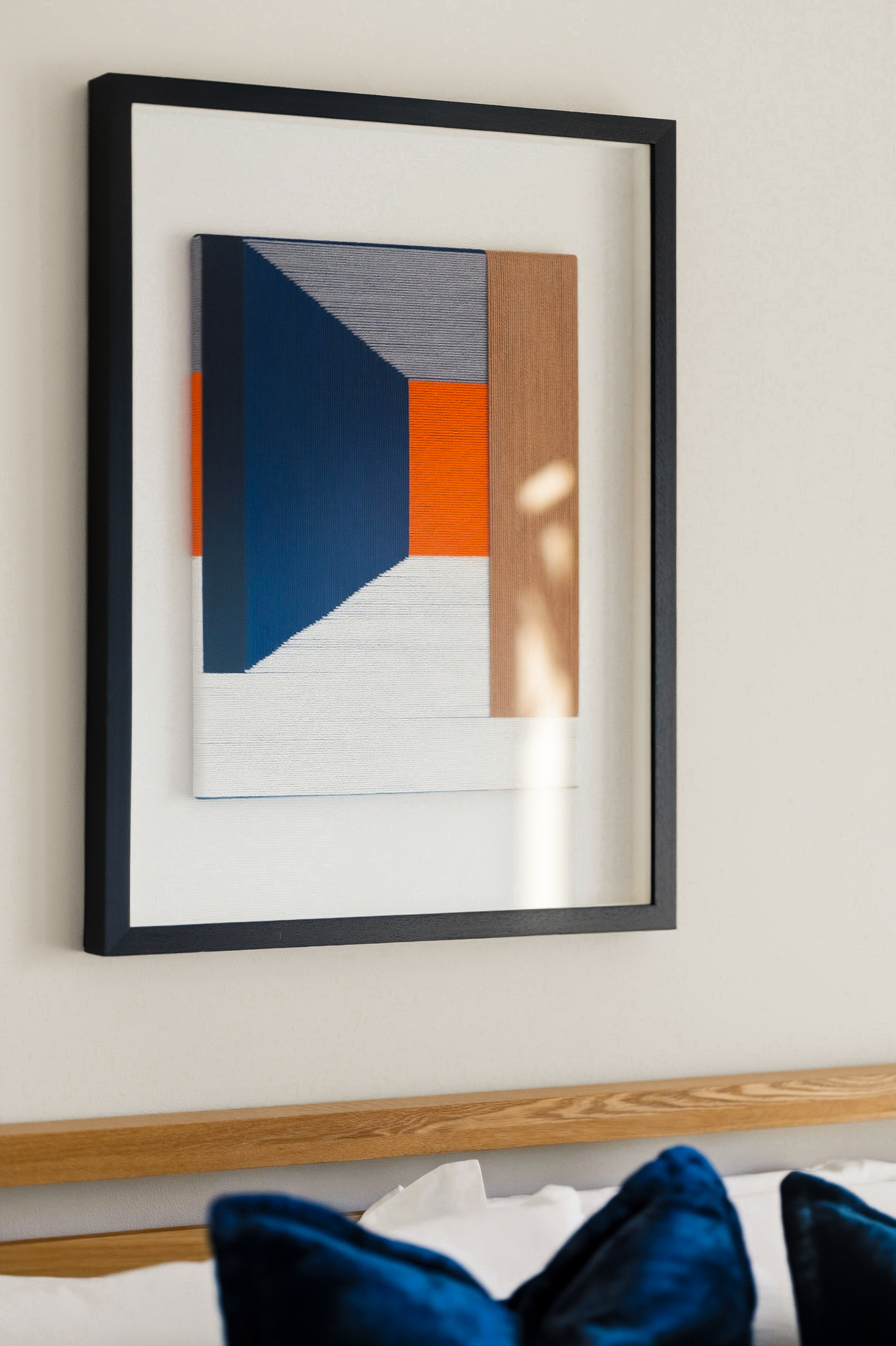 Modern abstract art and plush blue accents above the bed