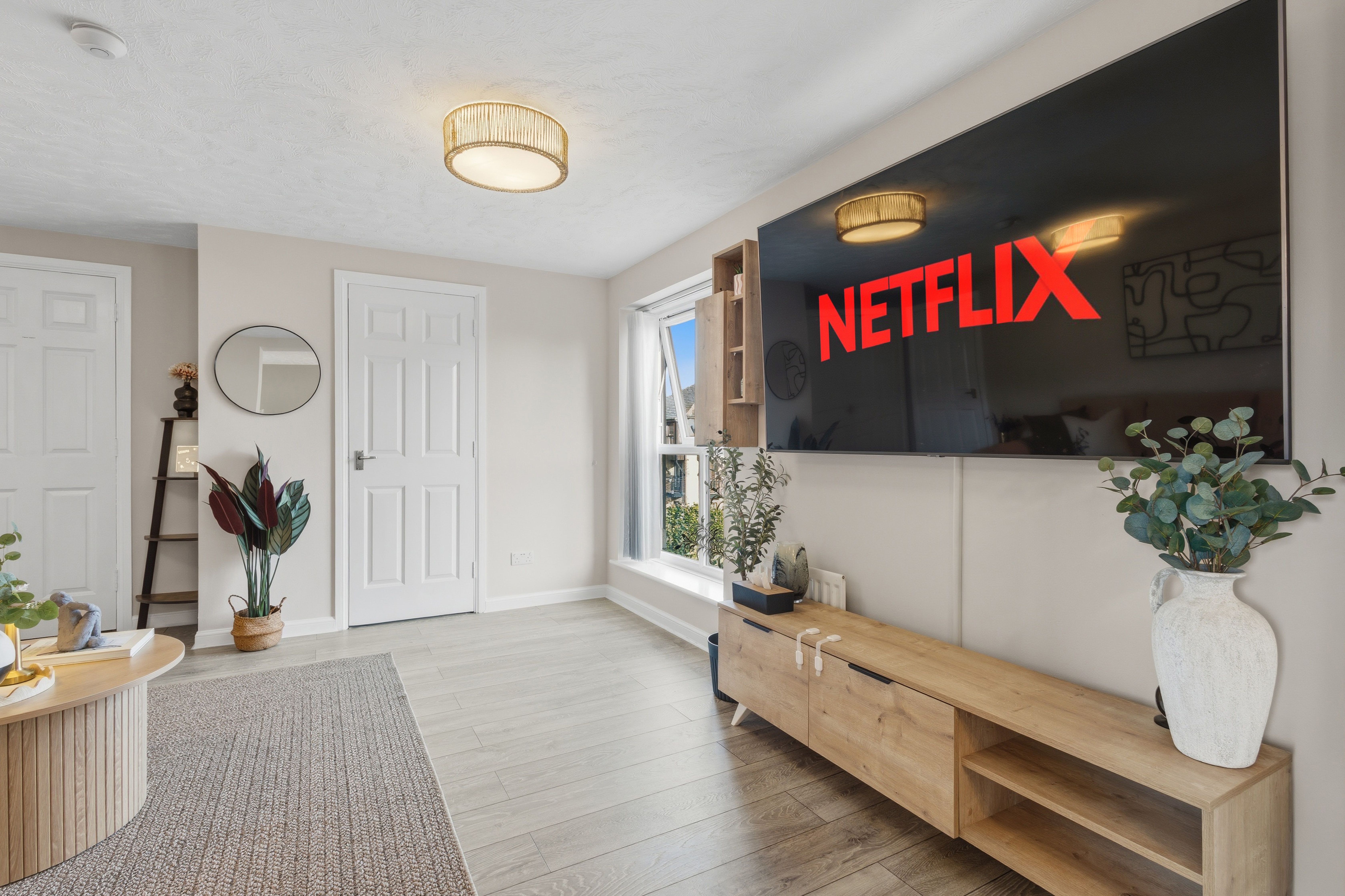 Bright modern lounge with large smart TV and stylish natural decor