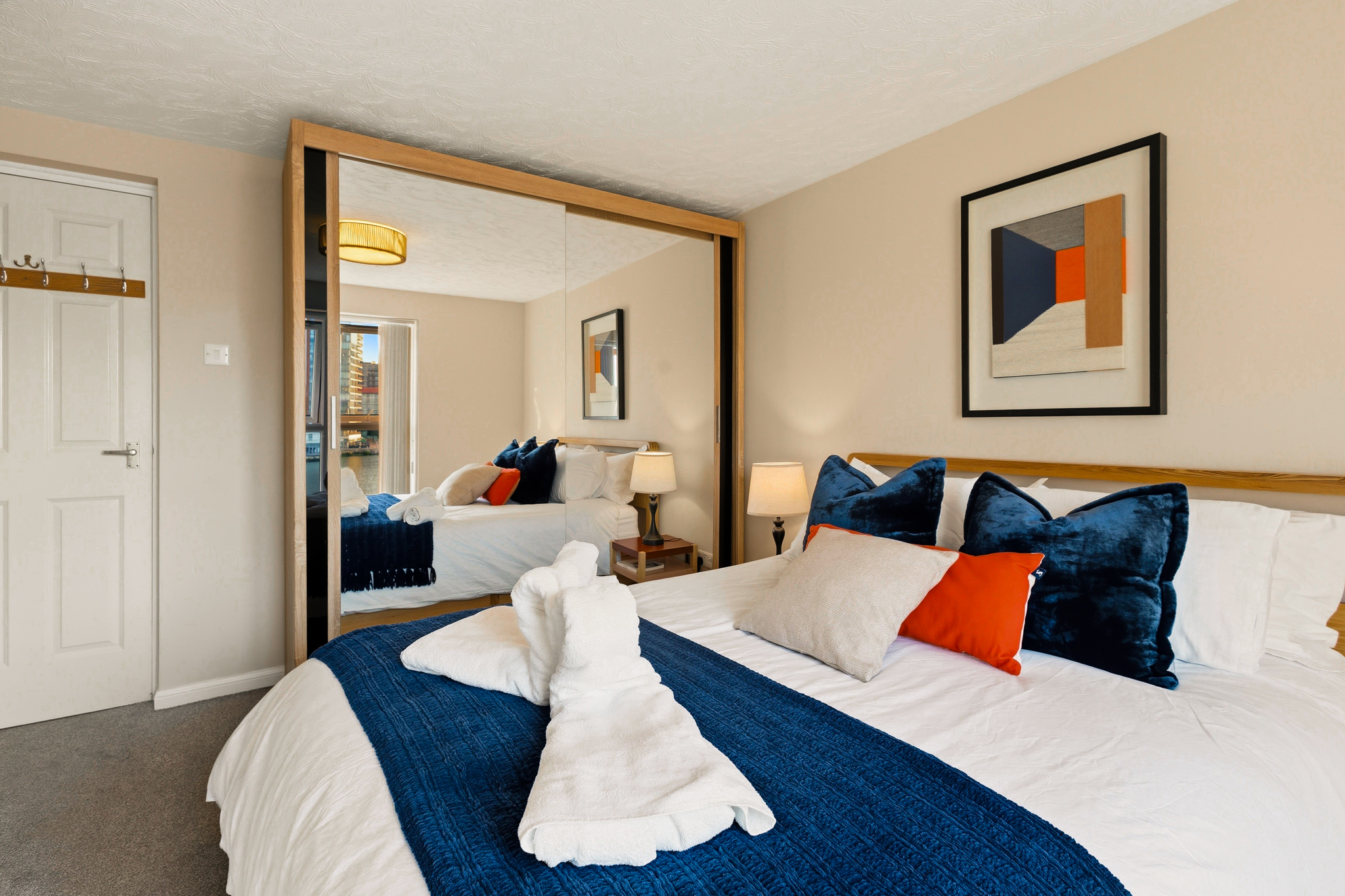 Bright stylish bedroom with mirrored wardrobe and plush king bed