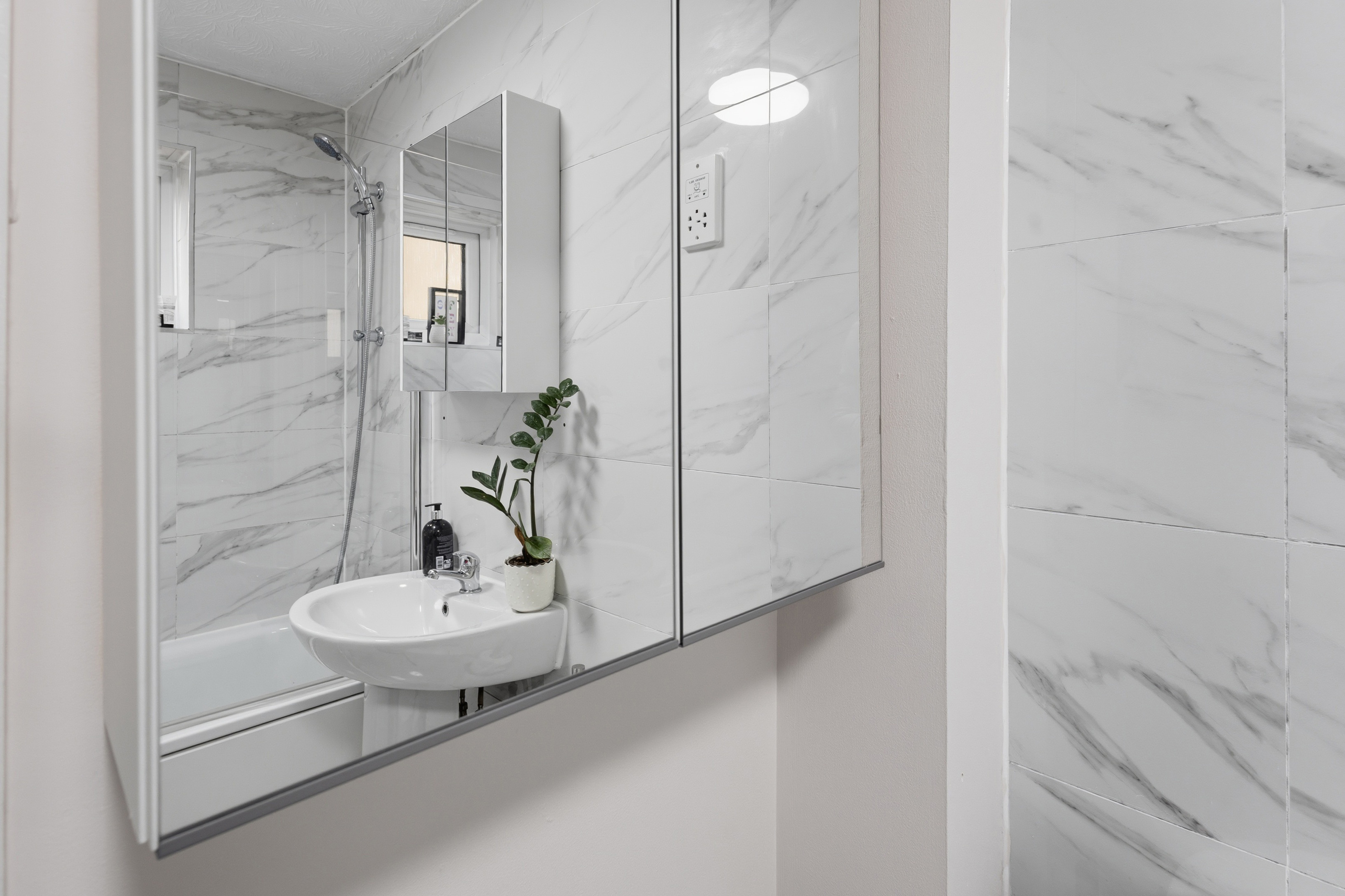 Bright modern bathroom with marble-style tile and tub-shower combo