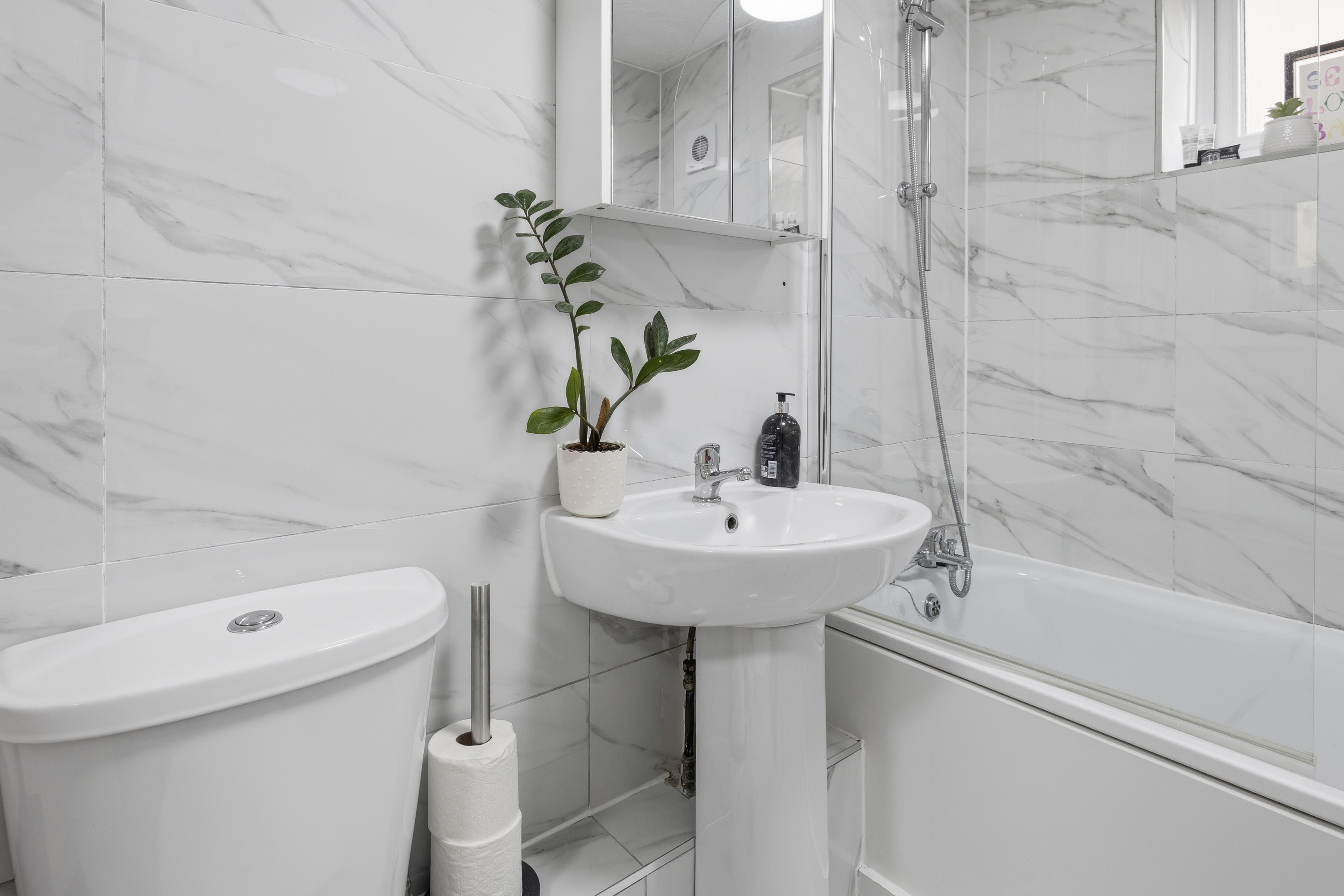 Bright modern bathroom with tub, shower, and elegant marble-style finishes
