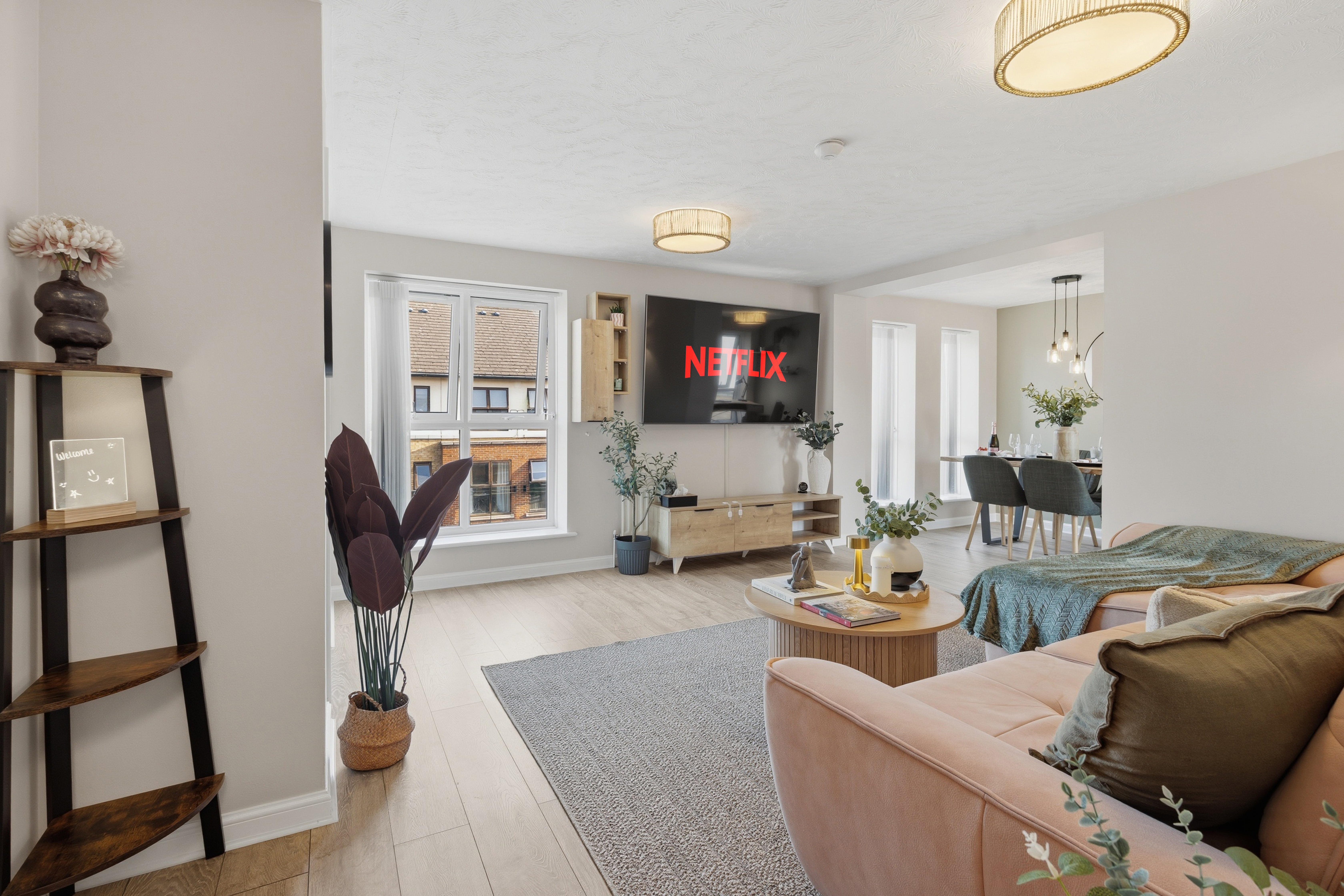 Bright open-plan lounge with large TV, dining area, and stylish modern décor