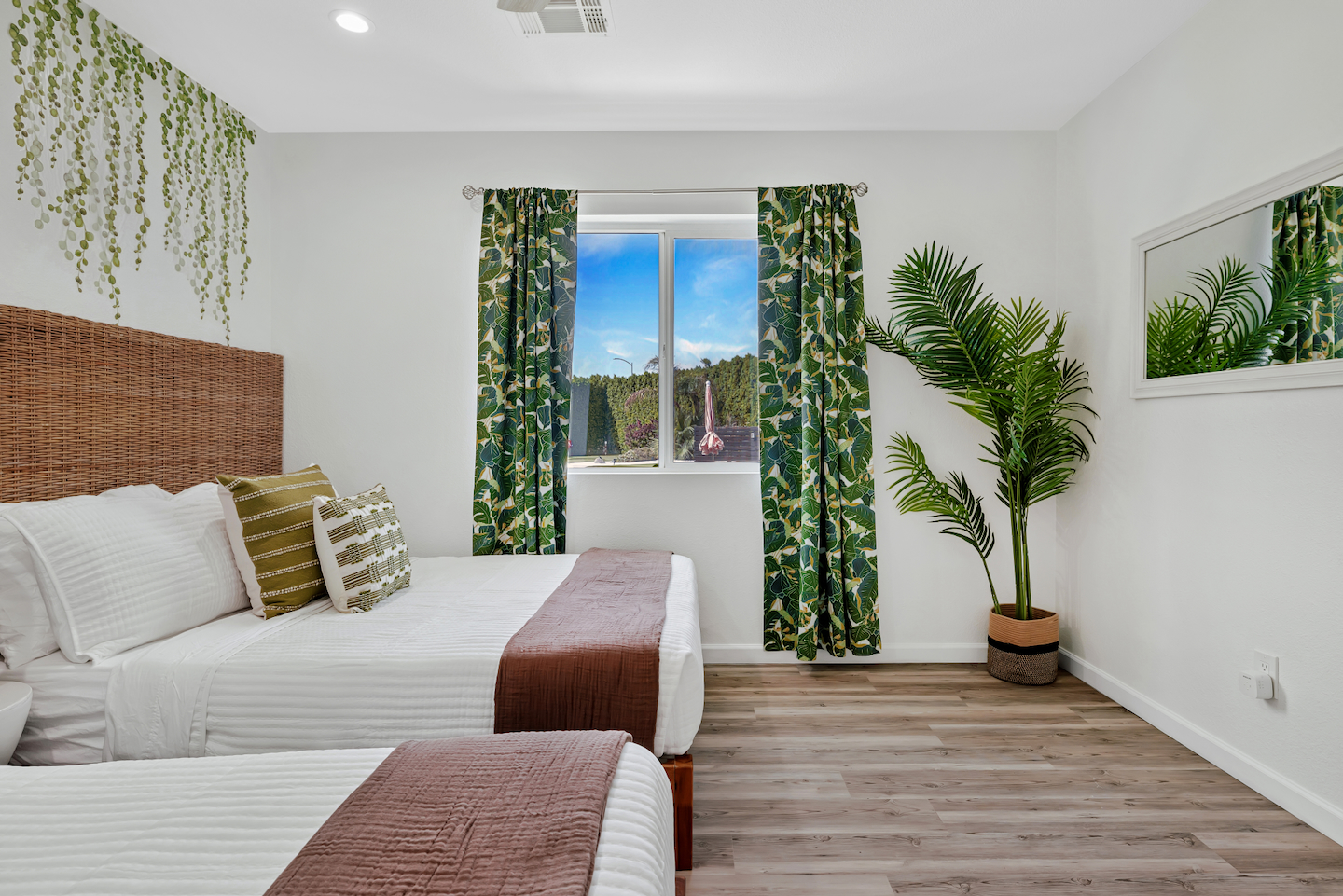 Bright tropical-inspired bedroom with two comfy beds and natural light