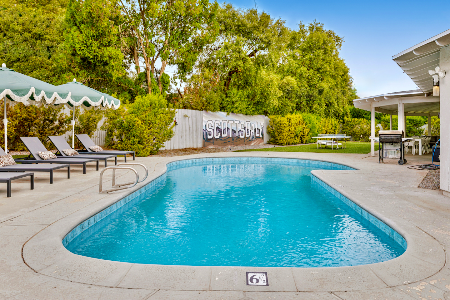 Private resort-style pool with loungers, shade umbrellas, and patio dining