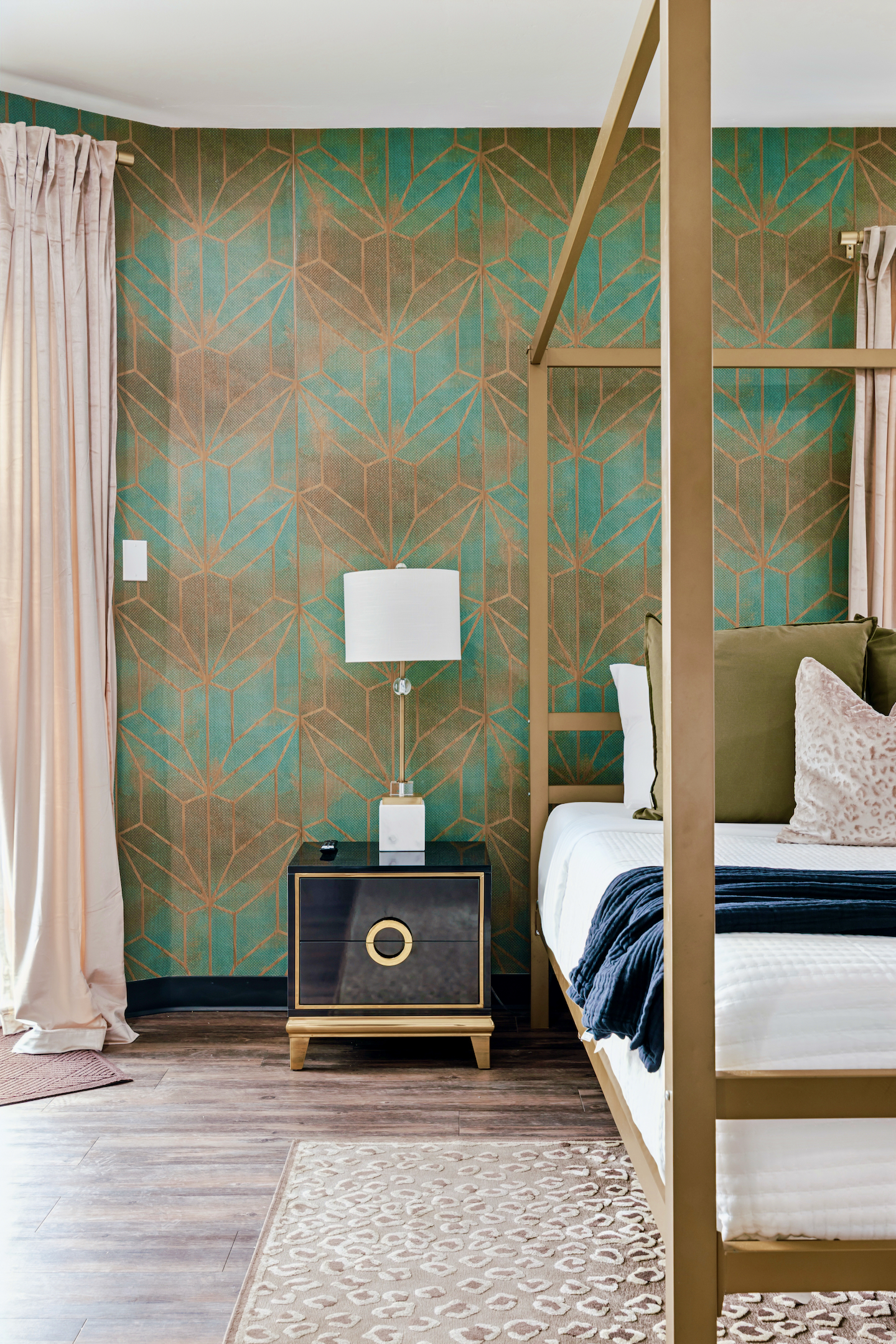 Primary suite nightstand with accent wallpaper and canopy bed