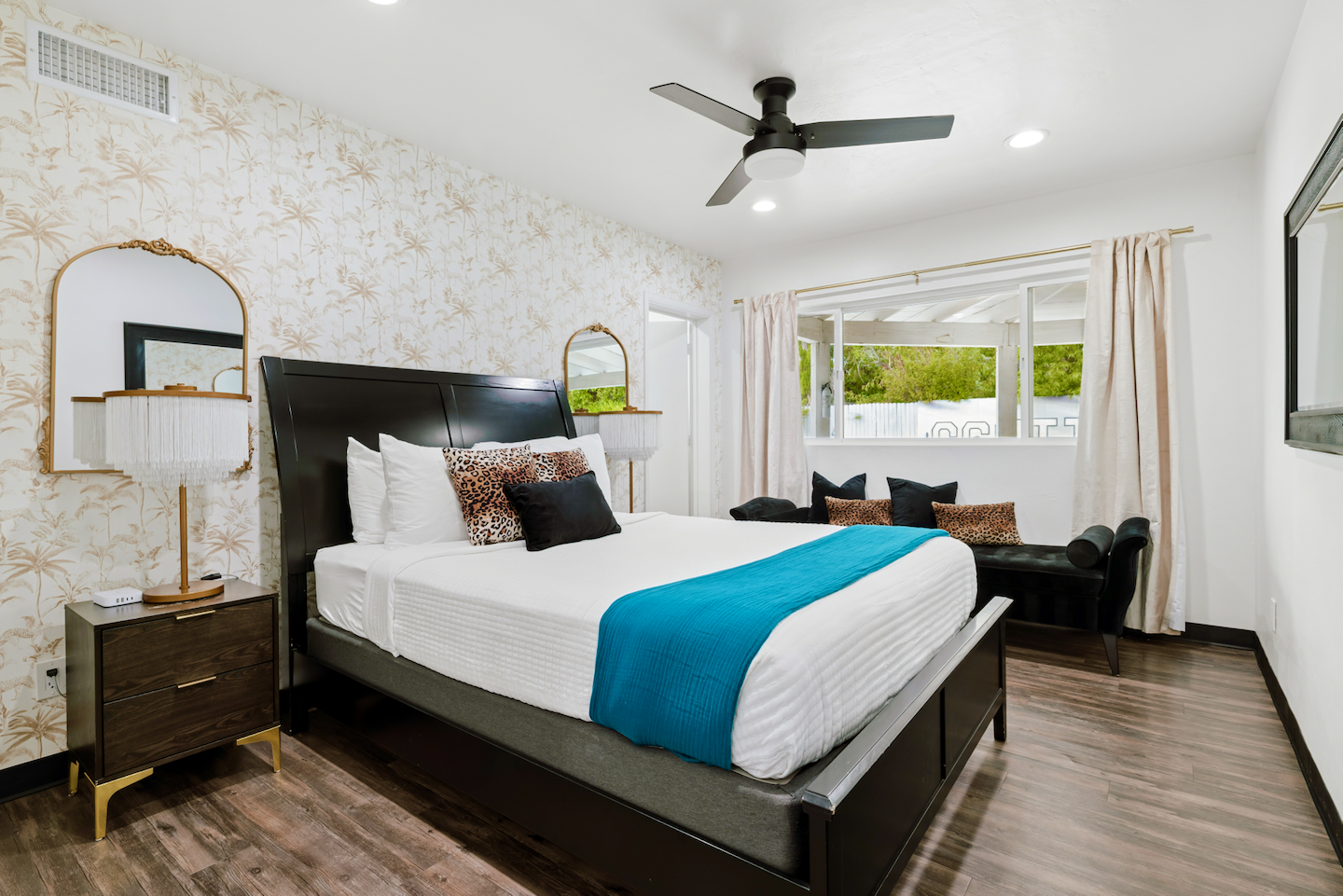 Queen bedroom with ceiling fan and chaise by the window