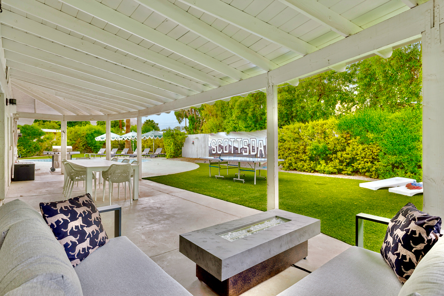 Spacious covered patio with fire table, lawn, and private poolside retreat