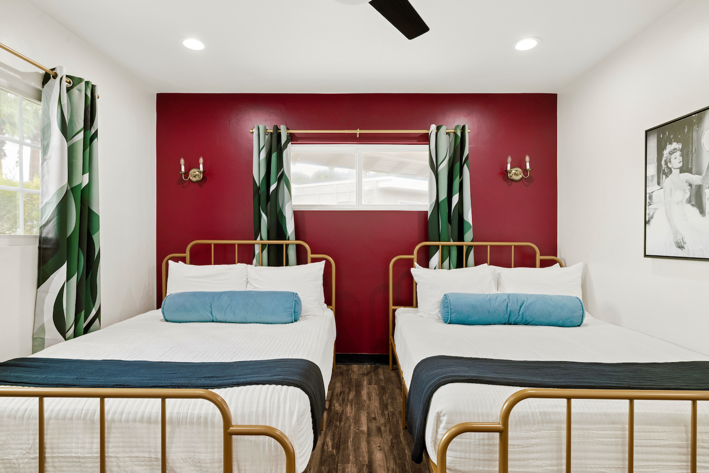 Two queen beds with gold frames and red accent wall