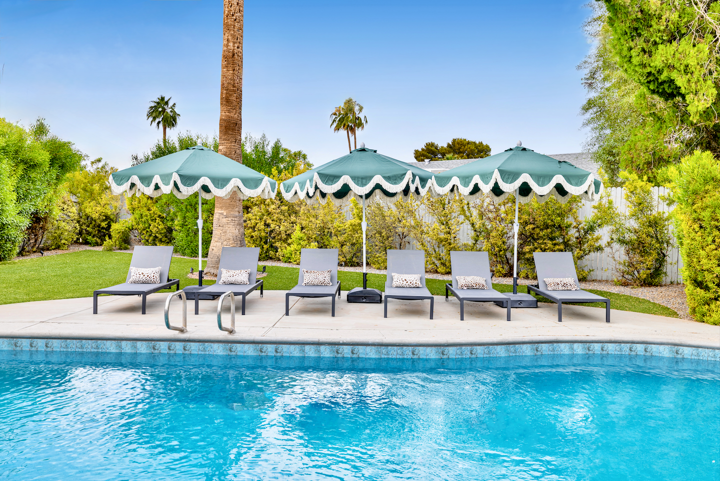 Resort-style pool with shaded loungers and lush palm-lined privacy