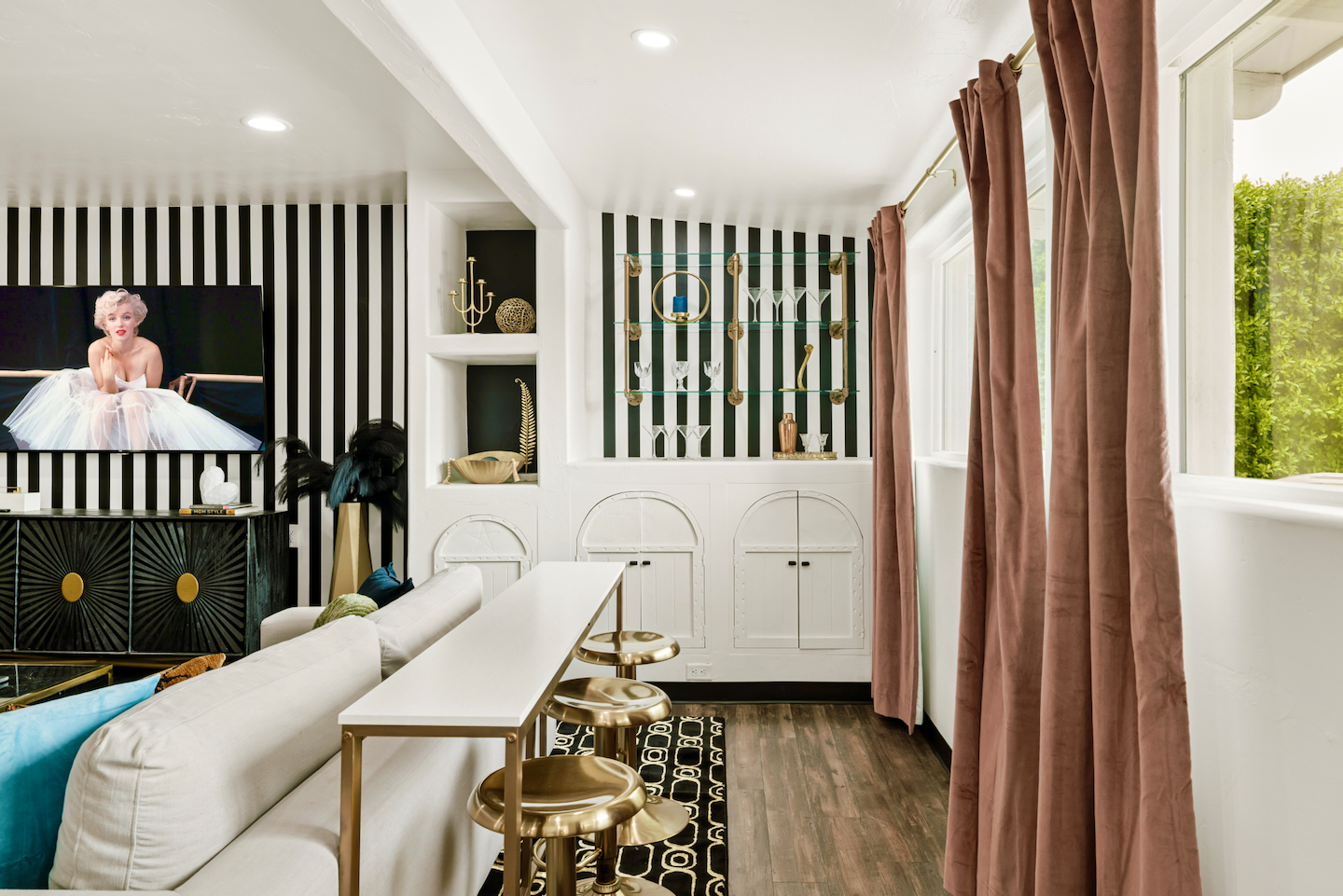 Living room sofa-table bar with gold stools and dry bar