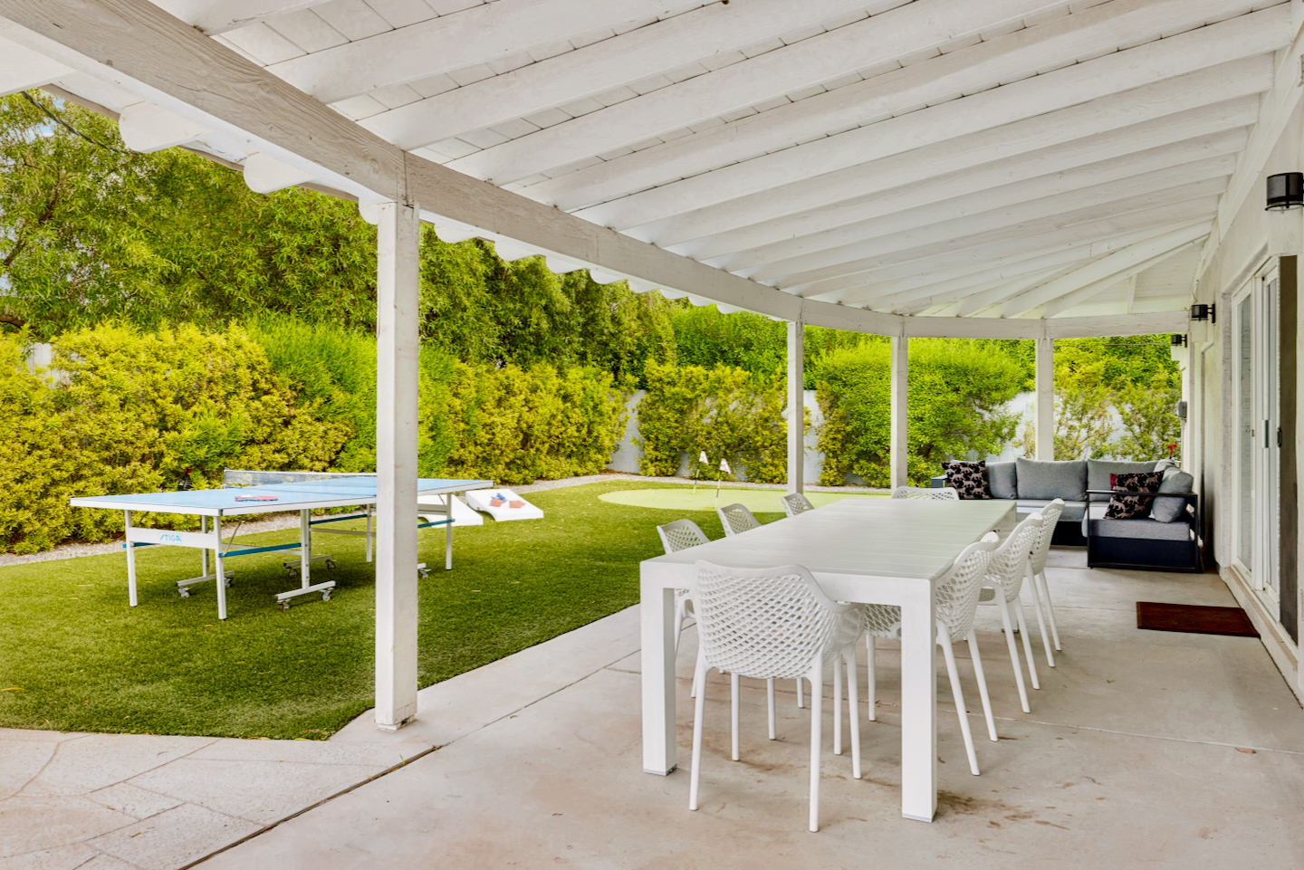 Covered patio with outdoor dining, lounge seating, and lawn games