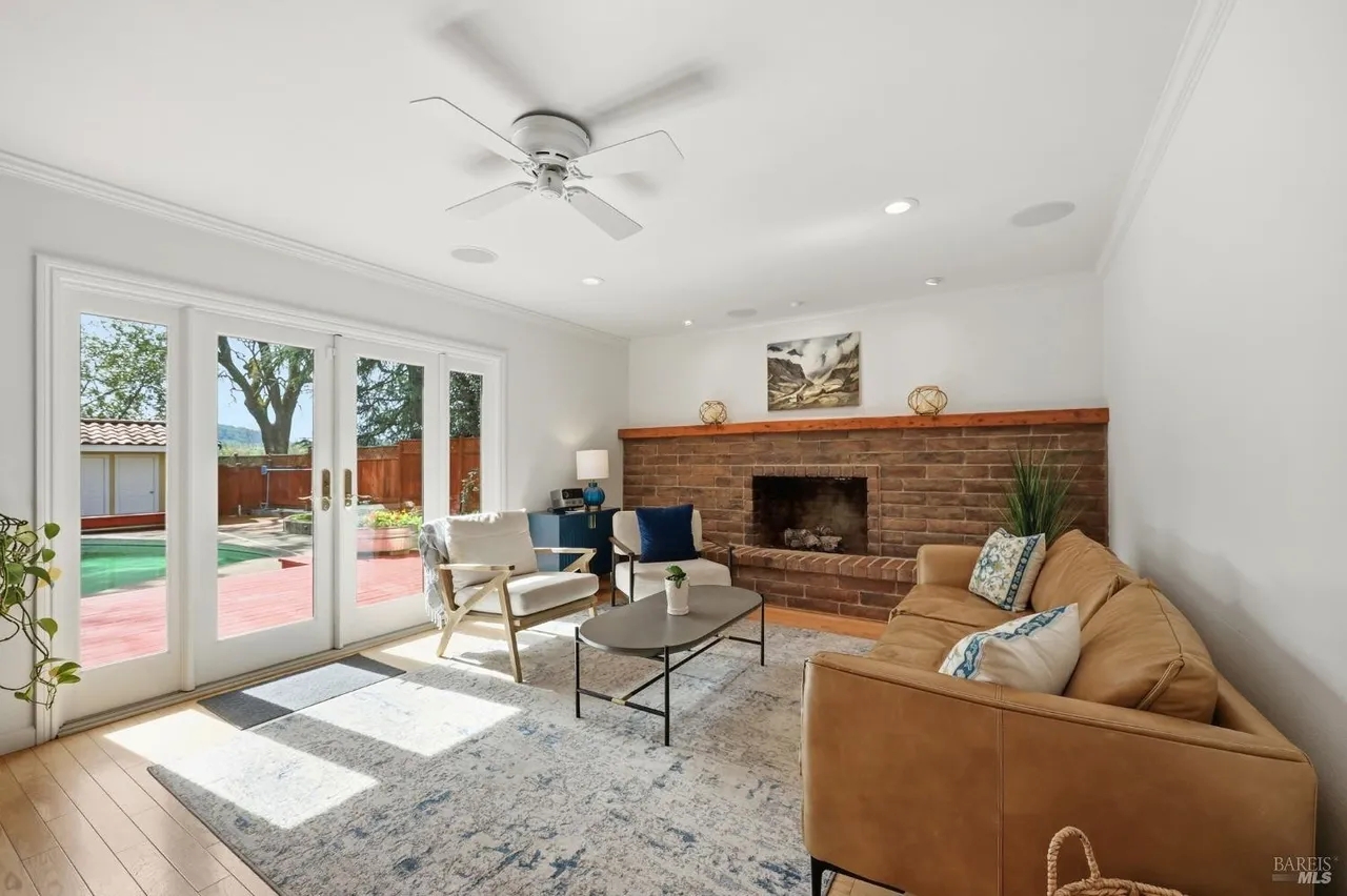 Bright living room with fireplace and French doors to the pool