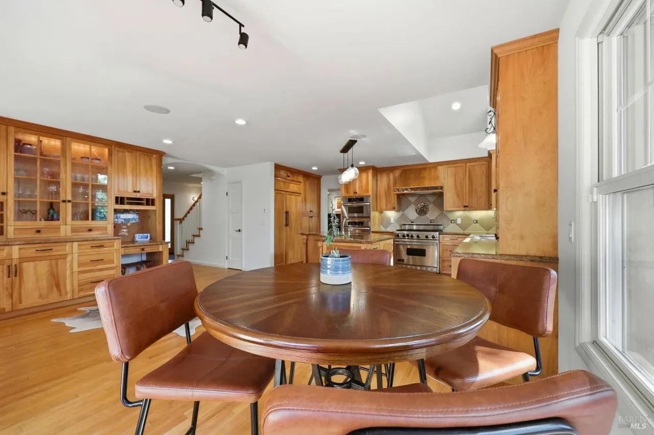 Warm open dining area with chef’s kitchen and elegant wood finishes