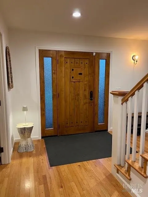 Bright entryway with hardwood floors and elegant wood front door