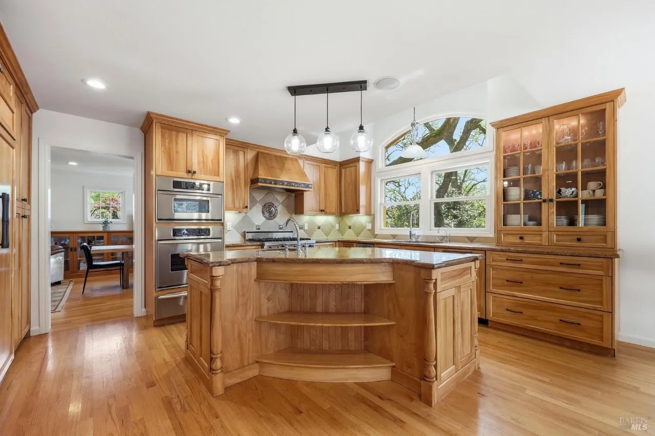 Bright chef’s kitchen with large island, hardwood floors, and sunny views
