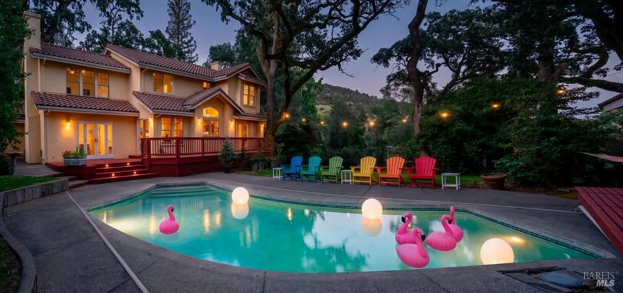 Twilight poolside oasis with string lights, deck, and private wooded setting