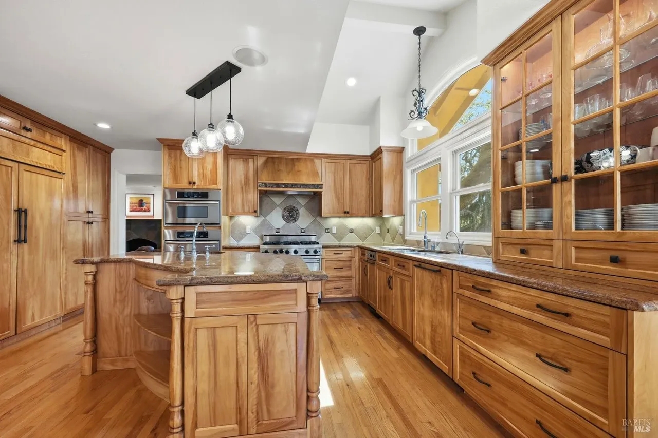 Bright gourmet kitchen with island, hardwood floors, and abundant cabinetry