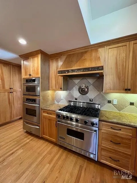 Chef’s kitchen with double ovens, gas range, and warm wood finishes
