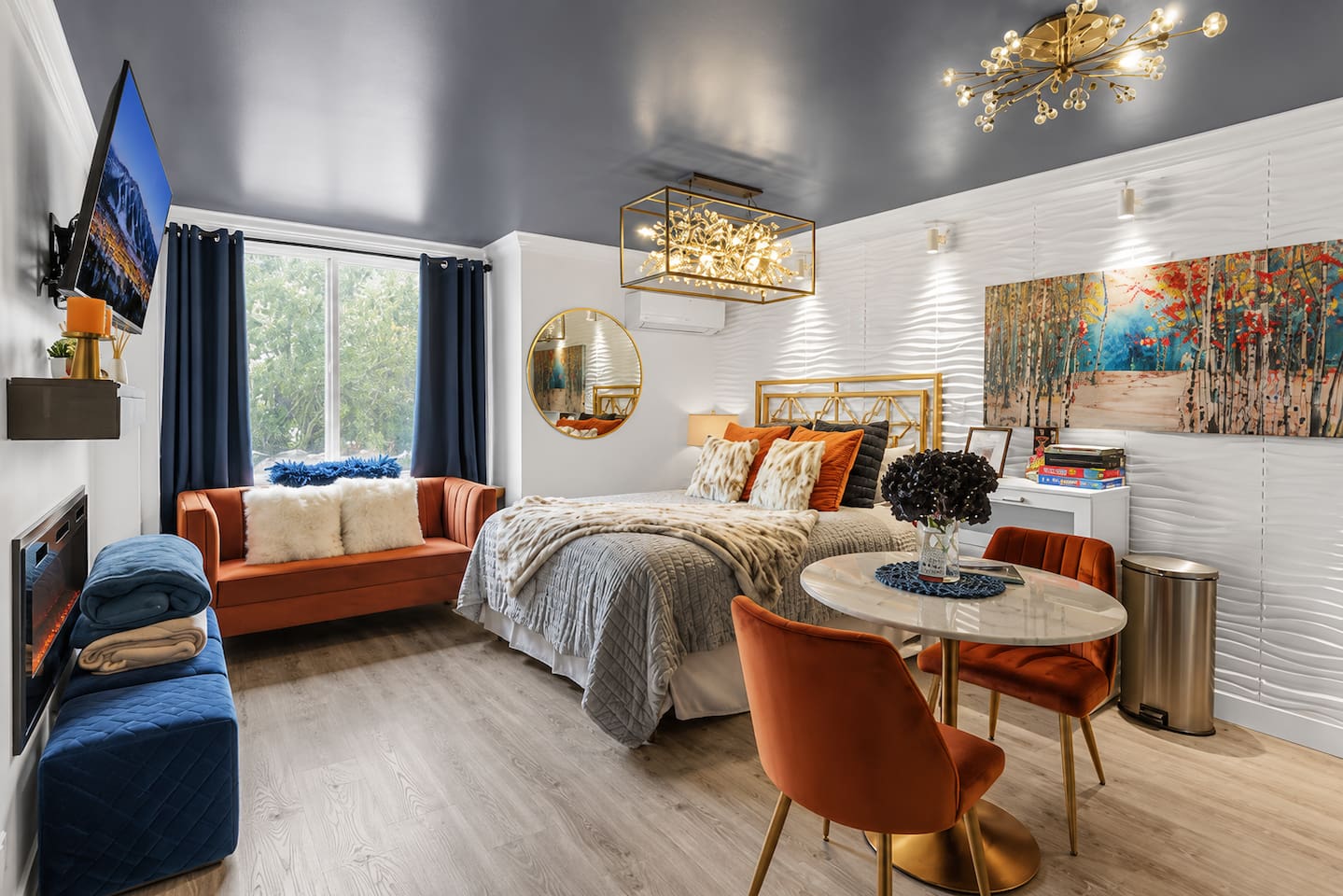Bright and stylish studio featuring a plush bed, cozy seating, Smart TV, and modern mountain-inspired décor.