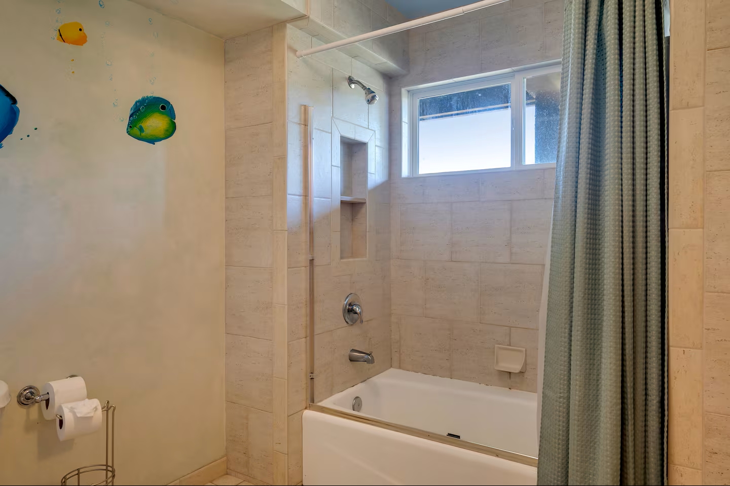 Bright tiled bathroom with tub-shower combo and natural light